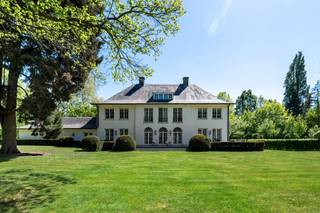 <p><span>Wonen in een groene oase zonder in te boeten aan comfort en bereikbaarheid. Ontdek deze karaktervolle, tijdloze en perfect onderhouden villa waar elegantie, licht en natuur harmonieus samenkomen. Dit eigendom onderscheidt zich door haar grote raampartijen die zorgen voor een zee van natuurlijk licht en een gevoel van openheid. Binnenstappen is thuiskomen in de grote en aangename leefruimtes, met zicht op de parktuin. De villa is gelegen op een perceel grond van ruim 1 ha met schitterend bomenbestand, aan een parallelwegje van de Bredabaan, tussen het centrum van Brasschaat en de Voshollei. </span></p><p><span> </span></p><p><span>Indeling</span></p><p><span>U betreedt de woning via de royale centrale inkomhal met gastentoilet en afzonderlijke vestiaire op stijlvolle natuurstenen vloer met trap naar de verdieping, en toegang tot drie verschillende leefruimtes met hoge plafonds en optimale lichtinval en openheid dankzij de talrijke royale raampartijen. De prachtige eiken parketvloer verleent deze vertrekken een tijdloze sereniteit. De gezellige woonkamer omvat een zitgedeelte aan de voorzijde van de villa met tv-hoek, en een tweede zitgedeelte met openhaard aan de achterzijde. Vervolgens is er toegang tot een stijlvolle eetkamer met tevens een prachtig uitzicht op de achtertuin. Vanuit deze eetkamer is er een doorgang naar een familyroom of bureau, eveneens met grote raamdeuren die uitgeven op het groen. Aan de voorzijde van de woning bevindt zich de leefkeuken, bestaande uit een functioneel ingerichte keuken en een ontbijthoek met toegang tot de voortuin. Vanuit de keuken hebt u ook toegang tot een volledige wasplaats of bijkeuken met mooie ingemaakte kasten en apart toilet met handenwasser, met aansluitend toegang tot de inpandige garages op gietvloer.</span></p><p><span> </span></p><p><span>Garage</span></p><p><span>De inpandige garage biedt plaats aan drie wagens, bevat een aparte bergplaats en is voorzien van automatische poorten.</span></p><p><span> </span></p><p><span>1e verdieping</span></p><p><span>Middels de ruime eiken trap in de inkomhal bereikt u de nachthal met licht en ruimte. Aan één zijde bevindt zich de mastersuite, bestaande uit een masterbedroom met zicht op de achtertuin, twee badkamers waarvan één badkamer met inloopregendouche, stijlvol lavabomeubel en toilet, en een andere badkamer met ligbad, lavabo en toilet, en een royale dressing met schitterende ingemaakte kasten. Een bijkomende kamer grenzend aan de mastersuite kan dienen als extra slaapkamer of hobbyruimte. </span></p><p><span>Aan de andere zijde van de nachthal bevinden zich nog twee ruime slaapkamers en een derde badkamer met ligbad en lavabomeubel. In de nachthal van deze zijde bevindt zich ook een apart toilet, alsook de toegang tot de diensttrap, die vertrekt vanuit de keuken en doorloopt tot de tweede verdieping.</span></p><p><span> </span></p><p><span>2e verdieping</span></p><p><span>Via deze diensttrap bereikt u de tweede verdieping, waar u een unieke meerwaarde vindt: een complete ruimte die perfect kan dienen als volwaardig appartement. Deze vertrekken kunnen naar wens worden ingericht als extra leefruimte, hobbykamer of bijkomende slaapkamers. Deze verdieping kan ook perfect gebruikt worden door bijvoorbeeld een inwonend familielid/ personeel/au-pair. Verschillende luiken op deze verdieping alsook één in de garage geven toegang tot de zolder.</span></p><p><span> </span></p><p><span>Kelder</span></p><p><span>De woning is helemaal onderkelderd en biedt o.m. bergruimtes, een wijnkelder, een waterverharder en een technische ruimte.</span></p><p><span> </span></p><p><span>Tuin en buitenruimtes</span></p><p><span>Het geheel biedt een mooie harmonie tussen binnen- en buitenleven dankzij de uitgestrekte zonneterrassen die uitnodigen om op elk moment van de dag te genieten van de rust en de groene omgeving. Met een prachtig terrein van ruim één hectare (ca. 10.337 m²) geniet u immers van een ongeëvenaard gevoel voor ruimte en privacy. Het pand is afgeschermd dankzij de privaatweg en een geluidsisolerende haag tussen die weg en de Bredabaan en beschikt over een royale oprit met automatische toegangspoort en ruime parkeergelegenheid. Een belangrijk kenmerk van dit eigendom is de fraaie omheinde parktuin, met waterloop aan de achterzijde. De tuin is smaakvol aangelegd met volwassen beplanting, tuinverlichting en wordt ook uitstekend onderhouden. Voorts is er een discreet gelegen tuinhuisje voor het tuin- en terrasmateriaal.</span></p><p><span> </span></p><p><span>Locatie / bijzonderheden</span></p><p><span>De ligging is enerzijds gunstig voor uitvalswegen en biedt een veilige omgeving met goede zichtbaarheid en sociale controle, en is anderzijds ideaal om met de fiets de voorzieningen binnen de wijk Vriesdonk te bereiken. De E19 ligt op slechts enkele minuten afstand, en de woning is centraal gelegen t.o.v. het openbaar vervoer en de dorpskern van Brasschaat. De afwerking van deze villa is het bewijs van een verfijnde, recente verbouwing met hoogwaardige materialen en oog voor detail. De woning beschikt over een doordachte indeling en ademt stijl en warmte uit. Mits enkele aanpassingen, zoals de eventuele vernieuwing van de keuken, kan dit eigendom beschouwd worden als een zeer exclusief object.</span></p><p><span> </span></p><p><span>Meer inlichtingen via ons kantoor.</span></p><p><span> </span></p>