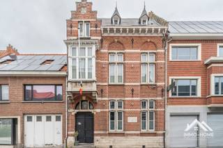 Deze prachtige herenwoning (ooit het eerste gemeentehuis van Overmere) ontvangt je in een majestueuze inkomhal. Je merkt hier meteen ook hoe het pand werd gerenoveerd met bijzonder veel zorg voor de authentieke elementen die overal in de woning nog prominent aanwezig zijn gebleven. De gelijkvloerse verdieping bevat een grote ontvangstruimte/bureel, waar de hoge plafonds voor een heel ruimtelijk gevoel zorgen. De prachtige haard vormt een heel mooi centraal sfeerpunt in deze ruimte. Achteraan is er voorzien in een kleine eerste keuken, een wasplaats en een overgangsruimte die naar de tuin leidt. Via de stijlvolle trap kom je tot op de eerste verdieping, waar het volledige leefgebeuren zich afspeelt. Centrale rol is daarin weggelegd voor de mooie open leefruimte met zithoek en leeshoekje, waar de combinatie van hoge plafonds, massiefhouten vloeren en zwarte details voor een tijdloos geheel zorgen. Achteraan bevindt zich de keuken met veel opberg- en werkruimte, en langs deze weg bereik je ook het leuke dakterras van waarop je uitkijkt op de mooie stadstuin. De twee verdiepingen erboven worden ingenomen door de slaapkamers : de eerste twee op de eerste laag, die zijn ingedeeld rond de badkamer met zowel sauna als een combinatie van hamman en douche. De master bedroom bevindt zich hierboven waar ze de volledige zolderverdieping inneemt. De combinatie van de oude dakbalken en de glazen ruimteverdeling zorgt voor een luxueuze uitstraling, en daar zorgt ook de en-suite badkamer met zowel ligbad als riante inloopdouche voor. Alle verdiepingen hebben ook een eigen apart toilet. Deze woning is zonder meer een pand waar wonen in stijl helemaal waarheid wordt !Bezoekdag 26/09: Inschrijven via mail naar stefan@immo-home.be, geen telefonische inschrijvingen! Volg ons op Fb en Insta. Voor meer info: www.immo-home.be. GRATIS SCHATTING & GRATIS FINANCIEEL ADVIES
