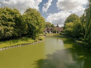 This exceptional domain is located a stone's throw from Roeselare's Grote Markt (only 2.5 km from a birds-eye view) and has an easy connection to the E403. For those looking for space, greenery, peace and lots of character, this is an excellent opportunity.This exclusive property includes a stately villa in castle farm style (built in 1976), a separate caretaker's house (approx. 201 m² living area) and various outbuildings, including stables and a party room. The villa has a generous living area of 683 m² and exudes rural elegance that immediately charms.Architectural elegance with romantic flair:white facades, elegant skylights, arched passageways, wrought iron ornaments, a massive wooden entrance door and characterful stained glass windows provide an authentic look with grandeur. The central tower acts as an architectural eye-catcher.Inside, the house offers, among other things:an impressive entrance hall with a long corridor | spacious living room with a view of the park garden | an office room and bedrooms on the ground floor | a kitchen with adjoining utility room | single-storey bathroom and solarium | multiple (bed) rooms on the first floor | a wine cellar and double garage...Outdoor life in a park garden with a pondThe living areas overlook the large pond and the surrounding park grounds, providing a permanent vacation feeling. The courtyard, surrounded by the buildings, garden wall and gateway, offers absolute privacy and a special atmospheric experience.Versatility and potentialThe caretaker's house is currently rented but will be vacant soon. The domain can be divided; buying with more or less land is negotiable. In addition, several spacious plots of land (recently parceled) border the whole, which are available separately for separate sale.A property with a soulThe presence of ancient antique architectural elements gives this villa an exceptional appearance. A unique property with countless options: ideal for refreshing or redeveloping into a luxurious private residence, combined living and working, space for horses or other animals, storage, and much more.Contact us for more info or a visit. You should experience this domain on site.