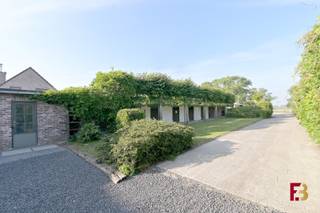 Paarden aan huis, zonder in te boeten aan wooncomfort? Deze eigendom combineert een <strong>grondig gerenoveerde woning met een bijzonder complete paardenaccommodatie</strong>, een aangelegde piste, paddocks en weides op ca.<strong> 1,2 hectare</strong>.<br /><br />De oorspronkelijke woning werd doorheen de jaren volledig gestript en gefaseerd vernieuwd. Niet alleen de zichtbare afwerking, maar ook de funderingen, vloeren, muren, elektriciteit, ramen en het dak werden aangepakt. Zonnepanelen, airconditioning en centrale verwarming op gas zorgen vandaag voor hedendaags wooncomfort.<br /><br />Binnen wacht een warme, karaktervolle leefomgeving met een <strong>ruime, volledig uitgeruste keuken</strong>, een gezellige zithoek, een recente badkamer met dubbele lavabo, ligbad en douche, praktische berging en <strong>drie slaapkamers</strong>.<br /><br />Eén van de slaapkamers bevindt zich op het gelijkvloers en beschikt bovendien over een <strong>eigen, rechtstreekse toegang van buitenaf</strong>. Ideaal als extra slaapkamer, maar evengoed als <strong>praktijkruimte voor een vrij beroep, thuiskantoor of afzonderlijke bureauruimte</strong>, zonder dat bezoekers door de privévertrekken hoeven.<br />Kwalitatieve materialen zoals natuursteen, keramische tegels en parket geven de woning extra uitstraling.<br /><br /><u><strong>Maar de absolute blikvanger bevindt zich buiten.</strong></u><br /><br />De paardenaccommodatie werd eveneens grondig vernieuwd en is praktisch ingericht voor wie zijn paarden professioneel of hobbymatig aan huis wil houden. Je beschikt onder meer over:
<ul>
<li>5 ruime paardenboxen, waaronder een grote merrie-veulenbox</li>
<li>camerabewaking in de stallen</li>
<li>zadelkamer/werkkot en voederberging</li>
<li>overdekte wasplaats</li>
<li>aparte opslag voor hooi en stro</li>
<li>mestopslag</li>
<li>automatische drinkbakken</li>
<li>gedraineerde buitenpiste van ca. 20 x 50 m met tapijtvezelbodem</li>
<li>3 verlichte zandpaddocks</li>
<li>ca. 1,2 ha volledig omheinde gronden</li>
<li>ledverlichting rondom de paardeninfrastructuur</li>
<li>regenwaterput van 15.000 liter voor de stallen</li>
</ul>
Ook aan het praktische aspect werd gedacht: de toegangspoorten zijn voorzien van elektrische sloten en parlofoon met bediening op afstand, er is een buitentoilet en aan de toegang tot de stallen werden Mudcontrol-tegels voorzien.<br /><br />Een eigendom voor wie droomt van <strong>wonen en paarden houden op één plek</strong>, met een infrastructuur die al klaarstaat.<br /><br /><strong>Een plek die je moeilijk in cijfers of foto's alleen kan vatten. Kom kijken, wandel door de stallen en langs de piste, en ontdek zelf hoeveel mogelijkheden hier samenkomen.</strong>