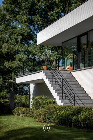 In de exclusieve woonparkomgeving van Bolderberg bevindt zich deze modernistische villa naar de hand van architect Francis Strauven, een meesterwerk van licht, rust en geavanceerde technologie. De in 2014 gerenoveerde eigendom onderscheidt zich door een hoogwaardige afwerking met materialen zoals massief noestenvrij parket, natuursteen en designaccenten van Antonio Lupi en Vola.<br />Het interieur vloeit naadloos over in de groene omgeving dankzij kamerhoge raampartijen met driedubbele beglazing. De woning biedt drie ruime slaapkamers en twee luxueuze badkamers, verdeeld over het gelijkvloers en het functionele souterrain, waar ook een privé-sauna en een garage voor drie wagens zijn ondergebracht. De Bulthaup-keuken met V-Zug toestellen vormt het culinaire hart van de woning, terwijl technieken zoals een geothermische warmtepomp, PV-panelen en een geavanceerd ventilatiesysteem zorgen voor een ongeëvenaard wooncomfort.<br />Buiten geniet u op het zuidgerichte perceel van bijna 30 are van optimale privacy en een weids zicht. Met een royaal arduinen terras en reeds aanwezige voorzieningen voor een zwembad, biedt dit domein alle ruimte voor een exclusieve levensstijl op een absolute toplocatie.