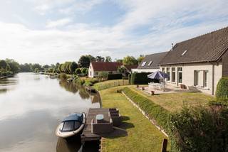 <strong>Exclusieve woning met privé-aanlegsteiger aan de Leie te St-Martens-Latem – Wonen alsof u elke dag op vakantie bent</strong><br /><br /><strong>Huurprijs</strong>: € 2.850/maand - <strong>Onmiddellijk beschikbaar</strong><br /><br />Wonen op een van de mooiste locaties van Sint-Martens-Latem? Deze uitzonderlijk luxueuze woning biedt een ongeëvenaarde woonbeleving op een unieke ligging langs de Leie. Met een eigen aanlegsteiger, meerdere zonovergoten terrassen voor- en achteraan en een adembenemend uitzicht geniet u hier elke dag van een permanent vakantiegevoel. De woning bevindt zich op een uiterst rustige locatie, vlak bij het pittoreske Baarleveer, en combineert absolute privacy met een uitstekende bereikbaarheid.<br />Dankzij de grote raampartijen baadt de woning de hele dag in het natuurlijke licht. Bovendien werd ze uitgerust met alle hedendaagse comfort en duurzame technieken, waaronder <strong>10 zonnepanelen, een warmtepomp, vloerverwarming, airconditioning</strong> en een <strong>laadstation voor een elektrische wagen</strong>.<br /><br /><strong>Indeling</strong><br /><strong>Gelijkvloers</strong>
<ul>
<li><span>Lichtrijke leefruimte met gezellige houtkachel en prachtig zicht op de Leie</span></li>
<li><span>Moderne, volledig ingerichte keuken met kwalitatieve inbouwtoestellen en een centraal keukeneiland, de ideale plek om gezellig te ontbijten, lunchen of dineren</span></li>
<li><span>Slaapkamer met stijlvolle maatwerkkasten en een geïntegreerd bureau</span></li>
<li><span>Badkamer</span></li>
<li><span>Praktische berging</span></li>
<li><span>Vestiaire met ingemaakte kasten</span></li>
</ul>
<strong>Verdieping</strong>
<ul>
<li><span>Royale master bedroom van ca. 26 m²</span></li>
<li><span>Badkamer met lavabo, douche en toilet</span></li>
<li><span>Polyvalente kamer van ca. 24 m², ideaal als bureau, hobbyruimte of logeerkamer, voorzien van een ingemaakte kastenwand</span></li>
</ul>
<strong>Extra troeven</strong>
<ul>
<li><span>Unieke ligging aan de Leie - Eigen privé-aanlegsteiger</span></li>
<li><span>Meerdere terrassen voor- en achteraan</span></li>
<li><span>Zeer rustig, zonnig en uitzonderlijk lichtrijk</span></li>
<li><span>Luxueuze afwerking met hoogwaardige materialen</span></li>
<li><span>Warmtepomp</span></li>
<li><span>Vloerverwarming</span></li>
<li><span>Airconditioning</span></li>
<li><span>10 zonnepanelen</span></li>
<li><span>Wandlaadstation voor elektrische wagen</span></li>
</ul>
Een woning als deze komt slechts uitzonderlijk op de huurmarkt. Hier woont u in alle rust, omringd door natuur en water, zonder in te boeten aan luxe of comfort. Wie hier woont, waant zich werkelijk <strong>elke dag op vakantie</strong>.<br /><br /><strong>Interesse?</strong><br />Voor meer informatie of een bezoek ter plaatse kunt u contact opnemen via <strong>tine@tvevastgoed.be</strong> of telefonisch via <strong>0474 97 00 22</strong>.<br />