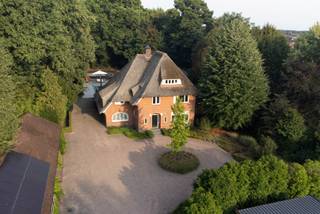 Deze karakteristieke en indrukwekkende villa op een perceel van 55a62ca (5.562 m²) wordt verkocht!<br /><br />De villa bevindt zich op een fijne locatie in Hamont-Achel, op loopafstand van het centrum en recht tegenover het gezellige stadspark met speeltuin en tennispark.<br /><br />Zodra we de oprijlaan zien, merken we direct dat dit pand een uniek pareltje is. Via een automatische poort rijden we het perceel op, voorzien van prachtige groenaanplanting, tuinverlichting en volledige privacy. Aan de voorzijde bevindt zich een ruime overkapping met laadpaal voor elektrische auto’s, momenteel ingericht als outdoor/overkapte gym, en met voldoende plaats voor het parkeren van meerdere auto’s. De villa is volledig omgeven door groen (eigen bos/bomen) en heeft een prachtig rieten dak. Rondom de volledige achtertuin bevindt zich een bos, met looppad en veel mogelijkheden om te spelen voor kinderen.<br /><br /><br />Buiten ademt de fraai aangelegde, onderhoudsarme tuin een gevoel van rust en luxe. Vanuit de leefruimte stapt u het terras op, waar het buitenleven zich in volle glorie ontvouwt. Het verwarmde zwembad kreeg vorig jaar een volledige renovatie: de installatie werd vernieuwd naar een zout- en magnesiumsysteem en het terras rondom is helemaal vernieuwd.<br /><br /><br />Naast het zwembad bevindt zich een barrelsauna die zowel Fins als infrarood kan worden gebruikt, ideaal om het buitenleven in alle seizoenen te beleven. Verspreid door de tuin liggen intieme zithoekjes, telkens met hun eigen sfeer. Voor kinderen en sportievelingen zijn er bovendien twee extra troeven: een ingebouwde trampoline en een professioneel aangelegd sport- en basketbalveld.<br /><br /><br />De villa (417m², volledig asbestvrij, elektriciteit conform 2025, EPC-label B met score 191) werd recent in 2024 volledig gerenoveerd, met focus op het behoud van de karakteristieke sfeer. Overal zijn radiatoren voorzien, er hangen 7 airco’s (voorzien om zowel te koelen als te verwarmen) en er zijn 16 zonnepanelen geplaatst op het bijgebouw.<br /><br /><br />Vanuit de royale inkomhal is er toegang tot het aparte toilet, een slaapkamer/bureauruimte, het verdiep en de leefruimte met open keuken. Deze leefruimte heeft een fantastisch zicht op de tuin, sluit naadloos aan op de eetkamer en is met behoud van karakter zeer elegant gerenoveerd. De keuken beschikt over een natuurstenen blad met kookeiland, is uitgerust met een Bora kookplaat, Quooker, alle nodige toestellen en extra’s, en valt op door de grote hoeveelheid lichtinval. In de leefruimte vinden we een mooie gashaard, ramen met glas-in-looddetails en een massief houten visgraatparket (gelegd in 2024).<br /><br /><br />Verder is er nog een tuinkamer (momenteel ingericht als home cinema, maar ook bruikbaar als bureau of slaapkamer) met prachtig zicht naar de tuin. Op het gelijkvloers vinden we daarnaast een wasruimte, voorzien van een handige linnenkoker vanuit twee slaapkamers boven, een doucheruimte en een apart toilet.<br /><br /><br />Op de eerste verdieping bevinden zich drie zeer ruime slaapkamers. De kleinste is 21m² en de grootste 50m², inclusief eigen zithoek. Twee slaapkamers beschikken bovendien over een dakterras. Alle slaapkamers zijn voorzien van sfeervolle en functionele inbouwkasten, recent geplaatst tijdens de renovatie van 2024. Verder is er een badkamer met bad en douche, en een apart toilet.<br /><br /><br />De tweede verdieping is volledig ingericht als master suite met badkamer-en-suite (bad en douche), een grote inbouwdressing en de mogelijkheid om ook hier een home cinema te voorzien.<br /><br /><br />De eerste en tweede verdieping zijn net als het gelijkvloers afgewerkt met een volledig massief houten visgraatparket (2024). Ook de trappen zijn professioneel gerenoveerd met massief hout, zodat alles perfect aansluit bij de warme en stijlvolle sfeer van de woning.<br /><br /><br />Tot slot beschikt de villa over een ruime kelder met meer dan voldoende opbergmogelijkheden.<br /><br /><br />Kortom: deze villa combineert uitzonderlijk wooncomfort met volledige privacy, een onderhoudsarme tuin, een unieke buitenomgeving en luxueuze extra’s — én dat alles op een toplocatie in Hamont-Achel.<br /><br /><br />Wenst u deze villa te bezichtigen? Contacteer ons via 011 64 55 00 of info@vastgoedfransen.be.