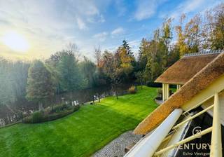 <p><strong>In de gegeerde residentiële verkaveling De Lint in Oud-Turnhout vinden we deze bijzonder ruime en charmante villa, ontworpen door architect Hertroijs. Een woning met klasse, warmte en een uitzonderlijke totaalbeleving—rustig wonen, maar toch centraal, op slechts 25 minuten van zowel Eindhoven als Antwerpen.</strong></p>
<p>De villa beschikt over een nieuwe rieten kap, goed voor decennialang zorgeloos wooncomfort. In de prachtig aangelegde tuin geniet u van een vernieuwd en verwarmd buitenzwembad en een sfeervolle vijver die het buitenleven een haast vakantiesfeer geven.<br />Bovendien is inruil van uw eigen woning mogelijk, wat de aankoop extra toegankelijk maakt.</p>
<p><span><strong>Indeling</strong></span><br />De ruime inkomhal vormt een stijlvolle entree, geeft uit naar het gastentoilet en de bureauruimte alsook naar de verschillende leefruimtes van de woning. De royale woonkamer baadt in natuurlijk licht en geniet dankzij grote raampartijen van een continu zicht op de tuin. De volledige gelijkvloerse verdieping is afgewerkt met een prachtige natuurstenen vloer in combinatie met vloerverwarming, wat zorgt voor een warm en luxueus wooncomfort.</p>
<p>De heerlijke leefkeuken, uitgerust met geïntegreerde eetkamer en een gezellige tv-hoek, vormt het hart van het huis. Aansluitend bevindt zich de praktische wasruimte met achterliggend een apart toilet en douche, ideaal voor zwembadgasten. Verder is er een inpandige garage voor twee wagens.</p>
<p>Op de verdieping bevinden zich vier slaapkamers, een afzonderlijke dressing en twee badkamers. De dressing werd oorspronkelijk als vijfde slaapkamer ingetekend en kan indien gewenst eenvoudig opnieuw als slaapkamer worden ingericht.<br />De hoofdslaapkamer beschikt over een ensuite luxe badkamer met ligbad, douche, toilet en dubbele wastafel. De tweede badkamer is gemeenschappelijk en bevindt zich aan de nachthal. Op deze verdieping werd deels gekozen voor een massief eiken parketvloer, wat de ruimtes een warme, tijdloze uitstraling geeft.</p>
<p><strong>Deze villa biedt een unieke combinatie van karakter, ruimte, luxe en natuurrust op een van de mooiste locaties van Oud-Turnhout. Een uitzonderlijke kans voor wie exclusief én comfortabel wil wonen.</strong></p>