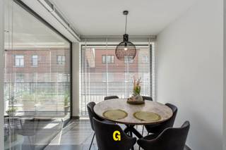 Dit knap ingericht appartement bevindt zich op het gelijkvloers in de zeer nette residentie Apollo, gelegen langs Hof ter Weyer ter hoogte van nummer 1. <br /><br /><br />LIGGING<br /><br />De ligging is zeer gunstig, vrijwel op wandelafstand van het gezellige dorpsplein van deze bloeiende gemeente, met in de directe omgeving bakkers, een slager, apothekers, gezellige eetadresjes en verschillende supermarkten. Het centrum van Bilzen ligt op slechts een drietal kilometer. Wie een vlotte verbinding zoekt met omliggende steden, vindt de oprit van de E313 op slechts 1,5 km. <br /><br /><br />RESIDENTIE APOLLO<br /><br />De residentie, daterende van 2018, is gebouwd volgens de hedendaagse normen van comfort en energiezuinigheid. Zowel de gevel als de afwerking van hal en gemeenschappelijke delen laten al onmiddellijk bij binnenkomst een nette degelijke stijlvolle uitstraling na, die men ook binnen in het appartement verder zal kunnen ervaren. In deze verzorgde residentie, waar iedereen gesteld is op rust en privacy, zal het aangenaam en gemoedelijk om wonen zijn. <br /><br />APPARTEMENT B03<br />Dit verzorgde, leuk ingedeelde appartement is gelegen op de gelijkvloerse verdieping, vlak aan de inkomhal en de lift, hetgeen dit appartement vlot toegankelijk maakt ook voor minder mobiele mensen. De huidige eigenaar heeft dit mooie eigendom smaakvol ingericht en voortdurend netjes onderhouden. Boven op de al verzorgde standaardafwerking werd nog geïnvesteerd in strak, knap afgewerkt inbouwmeubilair onder meer in de hal, slaapkamers en leefruimte. <br /><br /><br />INDELING/OMSCHRIJVING:<br /><br />-Verzorgde gemeenschappelijke inkomhal met lift.<br />-Privé inkomhal met gastentoilet en maatwerk vestiairekast<br />-Leuk ingedeelde leefruimte met lichtrijke eethoek, gezellige zithoek met strak afgewerkt inbouwmeubilair en details in houtwerk, toegang tot het terras<br />-Open ingerichte keuken met kookplaat, koelkast, oven en vaatwasmachine.<br />-Aansluitend: berging met aansluitingen voor wasmachine.<br />-Zuidgericht zonneterras (10 m² ) aan de voorzijde van het gebouw<br />-Eerste volwaardige slaapkamer gelegen aan de rustige achterzijde van het gebouw, noord gericht en netjes ingericht met een maatwerk dressingkast. <br />-Mooie badkamer met meubel en inloopdouche<br />-Tweede nog degelijk ruime slaapkamer, op heden ingericht als kapsalon, eenvoudig terug in te richten als slaapkamer. <br /><br /><br />Inbegrepen in de prijs zijn nog de standplaats en individuele berging in de kelderverdieping. <br /><br />Enkele technische kenmerken:<br />-EPC: 96,22 kWh:m² pj – label A<br />-Hoogrendementsketel aardgas – vloerverwarming<br />- Driedubbele beglazing in ALU raamprofielen<br />-Airco<br /><br /><br />Dit mooie eigendom kan een interessant aanbod zijn: <br />-Voor wie op zoek is naar een degelijk, recent en energiezuinig gelijkvloersappartement in een rustige serene residentie, comfortabel ingericht en knap afgewerkt, gunstig en centraal gelegen.<br />-Voor de investeerder die op zoek is naar aantrekkelijk appartement dat de nodige aantrekking zal genieten van een groot aantal geschikte kandidaat-huurders, met zicht op een mooi rendement - zonder aankomende kosten. Volledige, doorgedreven huurbegeleiding mogelijk via ons kantoor.