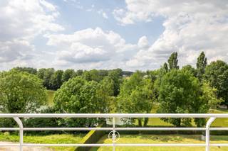 Op een toplocatie in Sint-Pieters-Leeuw bevindt zich dit uitzonderlijke penthouse met fantastische vergezichten over een natuurgebied en vijvers. Het penthouse met een hoge afwerkingsgraad werd afgewerkt met kwalitatieve materialen en maatwerk, waaronder parket, airconditioning, een centraal stofzuigsysteem en een zonnetenten.<br /><br />Het penthouse is als volgt ingedeeld: <br />Via de lift die gaat tot de private inkomhal, kom je terecht in de lichtrijke leefruimte met aparte tv-hoek, deze sluit via grote schuiframen naadloos aan op het ruime terras. De hypergeïnstalleerde keuken met aansluitende berging en wasruimte biedt alle hedendaags comfort. De master suite beschikt over een inloopdressing en een ensuite badkamer, terwijl de tweede slaapkamer een eigen douchekamer heeft. Een afzonderlijk bureau vervolledigt het gelijkvloerse woonniveau.<br /><br />Op de bovenverdieping bevindt zich een polyvalente ruimte die dienst kan doen als extra slaapkamer of bureauruimte, met berging en een indrukwekkend, rondom gelegen dakterras met buitendouche.<br /><br />Een extra troef is een afzonderlijke ruimte van 77 m² op het gelijkvloers. Deze ruimte biedt tal van mogelijkheden zoals een afzonderlijke kantoor- of praktijkruimte, een appartement voor een au-pair of als kangoeroewoning. Verder beschikt deze ruimte over zicht op de tuin, een eigen terras en een privatieve buitenparking. <br /><br />Tot slot beschikt deze unieke eigendom over een dubbele ondergrondse garage en drie private kelderbergingen, waaronder een wijnkelder.