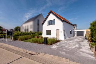 <p><strong>Volledig gerenoveerde villa met vier slaapkamers, gastenverblijf en zuidwestgerichte tuin aan de groene rand van Ravels. Aan de rand van Ravels, vlak bij de uitgestrekte Staatsbossen en op fietsafstand van het centrum, bevindt zich deze volledig gerenoveerde villa. De woning combineert een stijlvolle afwerking met bijzonder veel ruimte en hedendaags wooncomfort. Met onder meer vier slaapkamers, twee badkamers, een lichtrijke leefruimte met open designkeuken, een afzonderlijke kantoorruimte, een ruime garage en een instapklaar gastenverblijf is dit een uitzonderlijk veelzijdige eigendom. EPC label A</strong></p>
<p><strong>Gelijkvloerse verdieping</strong></p>
<p>De uitnodigende inkomhal met gastentoilet, sfeervolle indirecte verlichting en stijlvolle trappenhal verleent toegang tot de leefruimte. De woonkamer baadt dankzij de grote raampartijen in het natuurlijke daglicht. De ruime zithoek bevindt zich aan de straatzijde en biedt een aangenaam uitzicht op zowel de voortuin als de zijtuin. Centraal tussen de zithoek en de keuken ligt de eetkamer. amerhoge, dubbel opendraaiende deuren zorgen hier voor een rechtstreekse verbinding met de tuin en creëren een mooi samenspel tussen binnen en buiten. De open designkeuken is een absolute blikvanger. Ze werd uitgevoerd met gefineerde eiken kasten en binnenkasten in bijpassende kleur. De keuken is volledig uitgerust met een inductiekookplaat met geïntegreerde afzuiging in het werkblad, een vaatwasser, koelkast, afzonderlijke diepvriezer, spoelbak en oven. Het ruime composieten werkblad sluit naadloos aan bij het stijlvolle maatwerk. Dankzij de doordachte oriëntatie behoudt u tijdens het koken en tafelen contact met uw gezin of gasten en heeft u zicht op de oprit. Via de afzonderlijke zijingang bereikt u rechtstreeks de kantoorruimte. Deze toegang is voorzien van maatwerkkasten die dienstdoen als vestiaire en extra bergruimte, waardoor werken aan huis perfect mogelijk is zonder de privacy van de leefruimtes te verstoren. Een centrale gang vormt een rustig verbindingspunt tussen de leefruimte en het kantoor en geeft toegang tot twee ruime slaapkamers. Op deze verdieping bevindt zich bovendien een douchekamer, een afzonderlijk toilet en een praktische ruimte met aansluitingen voor een wasmachine en droogkast. De volledige gelijkvloerse verdieping is uitgerust met vloerverwarming. De aanwezige airconditioning zorgt tijdens de zomer voor aangename verkoeling en kan in de tussenseizoenen eveneens worden gebruikt om bij te verwarmen.</p>
<p><strong>Verdieping<br /></strong>Ook de bovenverdieping straalt rust en luxe uit. De natuurstenen vloer werd mooi doorgetrokken en versterkt het harmonieuze geheel. Hier bevinden zich twee ruime slaapkamers, die opengewerkt zijn tot in de nok van het dak en daardoor een bijzonder ruimtelijk karakter hebben. De stijlvolle badkamer is ingericht als een echte wellnessruimte en beschikt over een ruime inloopdouche, toilet en een dubbele wastafel met verlichte spiegel en praktische softclose-lades. Ook hier zijn aansluitingen voor een wasmachine en droogkast voorzien.</p>
<p><strong>Gastenverblijf en buitenruimte<br /></strong>Een bijzonder leuke verrassing is het afzonderlijke gastenverblijf achteraan in de tuin. Dit instapklare tiny house is bereikbaar via de tuin en vormt de ideale plek voor logés, inwonende kinderen, een hobbyruimte of een rustige werkplek. De verzorgde tuin is gunstig georiënteerd op het zuidwesten en biedt volop mogelijkheden om in alle rust van de zon en de groene omgeving te genieten. Daarnaast beschikt de woning over een ruime garage. De villa werd grondig en volledig vernieuwd en is onder meer voorzien van zonnepanelen, vloerverwarming en airconditioning in de leefruimte en slaapkamers. <br /><br />Bijzonderheden:<br />- Landelijke omgeving <br />- Volledig gerenoveerd, A label <br />- Zonnepanelen, Airco's <br />- Kindvriendelijke omgeving - op wandelafstand van natuurgebied Gewestbossen Ravels<br /><br /></p>
<p></p>