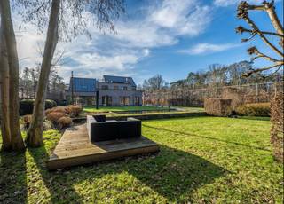 <p><strong>Quares by Trevi presenteert: Puur vakantiegevoel en privacy in een knappe villa aan het natuurgebied</strong></p>
<p>Geïnspireerd op de stijl van Piet Boon, kenmerkt deze villa zich door strakke architectuur, technische snufjes en kwaliteitsvolle, hoogwaardige materialen. Tijdloos design, mooie zichtlijnen en veel lichtinval zorgen voor rust en een direct vakantiegevoel. Topmaterialen zoals Corian, eik en notenhout sieren de woning. Domotica, warmtepompen, airco en een vingerafdrukscanner bieden modern comfort.</p>
<p><strong>De belangrijkste troeven op een rij:</strong></p>
<ul>
<li><strong>Toplocatie:</strong> Rustige, doodlopende straat aan een natuurgebied, vlak bij de Golf van Keerbergen.</li>
<li><strong>Wellness:</strong> binnenzwembad met jetstream & aansluitende badkamer, zwemvijver en luxe poolhouse.</li>
<li><strong>Ruimte:</strong> 6 slaapkamers, meerdere dakterrassen, home cinema en grote, droge kelder.</li>
<li><strong>Techniek:</strong> Uitgerust met warmtepompen, airco, domotica en camerabewaking.</li>
</ul>
<p><strong>INDELING</strong></p>
<p><strong>Gelijkvloers:</strong> Inkomhal met vestiaire en gastentoilet; wasplaats; bureau; royale leefruimte met open haard en tuinvisie; home cinema/eetkamer; inpandig west-terras met open haard. De luxe leefkeuken heeft een eiland, Gaggenau-toestellen, wijnkoeler en Quooker. Aansluitend ligt de wellnessruimte met binnenzwembad (ionisatie & jetstream, perfect werkend, nu afgedekt als relaxruimte) die baadt in het licht, en een badkamer met vrijstaand bad, douche en toilet.</p>
<p><strong>Kelder:</strong> Grote, droge kelder met actieve ventilatie, verdeeld in 6 ruimtes (ideaal als mancave, fitness, wijnkelder) plus de technische installaties.</p>
<p><strong>Eerste verdieping:</strong> Vijf slaapkamers met massieve parket en airco. De master bedroom heeft een en-suite dressing en privé-dakterras. Verder zijn er drie slaapkamers (waarvan één met terras), een zeer grote kamer boven het zwembad, apart toilet en een badkamer met ligbad, douche, bidet en dubbele lavabo.</p>
<p><strong>Tweede verdieping:</strong> Zesde slaapkamer of studio met toegang tot een groot dakterras achteraan en een terras vooraan.</p>
<p><strong>Buitenruimte:</strong> Volledig omheind perceel met automatische poort. Oprit voor 4 auto's, garage en berging. Het poolhouse heeft een douche, toilet, berging en overdekt terras met infraroodverwarming. De tuin biedt diverse terrassen, een zwemvijver met circulatiepomp en een origineel tuinhuis waarin een boom geïntegreerd is.</p>
<p>Heb je interesse? Maak een afspraak met Tinne Schotsmans op <strong>0477 60 21 99</strong> of via <strong>tinne.schotsmans@quares-trevi.be</strong>.</p>
<p></p>