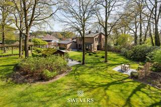 Voor meer info en foto’s, surf naar www.swevers.be – Deze ruime open bebouwing aan de Koerselsesteenweg 146 in Beringen combineert comfortabel wonen met professionele mogelijkheden. Dankzij aparte ingangen voor het privé- en praktijkgedeelte is de woning ideaal voor een zelfstandige activiteit aan huis, maar ook geschikt voor kangoeroewonen. De woning dateert van 1980 en werd doorheen de jaren gericht vernieuwd, met onder meer een nieuw pannendak, gerenoveerde living en keuken, vernieuwde condensatieketel, drie nieuwe Veluxramen en zonnepanelen uit 2023. Met een bewoonbare oppervlakte van 340 m² is er bijzonder veel ruimte. Op het gelijkvloers bevinden zich een woonkamer met eetkamer van samen 46 m², een keuken van 16,40 m², bureau en apart toilet. Het praktijkgedeelte omvat een wachtruimte, consultatieruimte, archief/doka en eigen toilet. Daarnaast zijn er een inpandige garage van 42 m² en een ruime berging. De eerste verdieping telt vier slaapkamers van 12,5 tot 22 m², waarvan één met terras en één met ingemaakte kasten. Verder zijn er een badkamer en apart toilet. De kelder van 44 m² zorgt voor extra bergruimte. Het perceel van 37a 75ca beschikt over een groen aangelegde tuin met meerdere terrassen en tuinhuisjes. Er is parkeerruimte voor 8 à 10 wagens. Scholen, openbaar vervoer en de snelweg zijn vlot bereikbaar. Extra troeven zijn het alarmsysteem, rolluiken, zonnewering en een beveiligde deur. Voor meer informatie, bel 011 255 155. Bron bewoonbare oppervlakte: EPC – verslag.