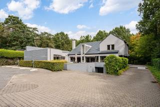 <p><span>Ruime op te frissen woning met 4 slaapkamers, wellness, dubbele garage en tal van mogelijkheden!</span></p><p><span> </span></p><p><span>Deze bijzonder ruime woning combineert een royale bewoonbare oppervlakte met tal van mogelijkheden en een uitstekende bereikbaarheid. De woning is momenteel ingericht als</span></p><p><span>kantoorruimte, maar beschikt over een volwaardige residentiële indeling en kan opnieuw worden ingericht tot een comfortabele gezinswoning.</span></p><p><span> </span></p><p><span>Op het gelijkvloers bevindt zich een ruime inkomhal met gastentoilet. Aan de linkerzijde vinden we een afzonderlijke bureauruimte, ideaal als thuiskantoor of praktijkruimte.</span></p><p><span>De royale leefruimte biedt plaats aan zowel een ruime eetplaats als een aparte, gezellige zithoek met gashaard alsook een TV-ruimte.</span></p><p><span>Grote raampartijen zorgen voor veel natuurlijk licht en zijn op het gelijkvloers voorzien van zonneluifels. De woning is hoofdzakelijk afgewerkt met tegelvloeren en beschikt over in de vloer geïntegreerde convectoren.</span></p><p><span>De zeer ruime keuken biedt veel werk- en bergruimte en geeft via de achterdeur rechtstreeks toegang tot het terras en de tuin. Aansluitend bevinden zich nog een praktische berging en bijkeuken.</span></p><p><span>Een absolute troef is de grote polyvalente ruimte, momenteel ingericht met een bar. Onder de huidige vloer bevindt zich het oorspronkelijke binnenzwembad. De vloerconstructie kan opnieuw worden verwijderd, waardoor het zwembad opnieuw in gebruik kan worden genomen en hier een prachtige ontspanningsruimte kan worden gecreëerd. Aansluitend bevindt zich een aparte wellnessruimte met stoomcabine en sanitair.</span></p><p><span> </span></p><p><span>Op de verdieping bevinden zich vier volwaardige slaapkamers. De master bedroom beschikt over ingebouwde kasten. Eén van de slaapkamers heeft een eigen douchekamer. Daarnaast is er een ruime badkamer met ligbad, douche, lavabo en toilet. Ook de verdieping is hoofdzakelijk voorzien van tegelvloeren.</span></p><p><span> </span></p><p><span>Ook aan praktische ruimte is er geen gebrek. De woning beschikt over een zeer ruime, volledig betegelde kelder en een dubbele inpandige garage, rechtstreeks bereikbaar via de oprit.</span></p><p><span> </span></p><p><span>Voor extra comfort is zowel op het gelijkvloers als op de verdieping airconditioning aanwezig. Daarnaast beschikt de woning over een alarmsysteem, een gashaard en werd de verwarmingsinstallatie ongeveer vier jaar geleden vernieuwd.</span></p><p><span>Ook energetisch is er een belangrijke troef: de woning heeft een EPC-score van C, waardoor er geen renovatieverplichting van toepassing is.</span></p><p><span> </span></p><p><span>Buiten valt meteen de uitzonderlijk ruime parking aan de voorzijde op, met plaats voor meerdere wagens. Achteraan geniet u van een mooi terras en een ruime, groene tuin. De achterliggende groene omgeving zorgt bovendien voor een aangenaam en open karakter.</span></p><p><span> </span></p><p><span>De woning kan op bepaalde punten naar eigen smaak worden opgefrist, maar biedt dankzij haar uitzonderlijke ruimtes, vier slaapkamers, binnenzwembad en wellnessmogelijkheden, dubbele garage en ruime buitenomgeving bijzonder veel potentieel. Ook voor wie wonen en werken wil combineren, biedt dit pand interessante mogelijkheden.</span></p><p><span> </span></p><p><span>Troeven:</span></p><p><span> - EPC-score C  geen renovatieverplichting</span></p><p><span> - 4 slaapkamers</span></p><p><span> - Zeer ruime leefruimtes</span></p><p><span> - Grote keuken met aansluitende berging en bijkeuken</span></p><p><span> - Binnenzwembad aanwezig onder de huidige vloer</span></p><p><span> - Wellnessruimte met stoomcabine</span></p><p><span> - Airconditioning op gelijkvloers en verdieping</span></p><p><span>- Gashaard</span></p><p><span> - Vloerconvectoren</span></p><p><span>- Verwarmingsinstallatie ca. 4 jaar geleden vernieuwd</span></p><p><span>- Grote, volledig betegelde kelder</span></p><p><span> - Dubbele inpandige garage</span></p><p><span>- Uitzonderlijk ruime parking vooraan</span></p><p><span> - Mooi terras en groene tuin</span></p><p><span>- Achterliggende groene omgeving</span></p><p><span>- Alarmsysteem</span></p><p><span> - Interessant voor combinatie wonen en werken</span></p><p><span> - Goede bereikbaarheid</span></p>