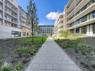 <strong>Nieuwbouw appartement met ruim terras </strong>(ca. 12m2) op het zuiden, gelegen aan het gloednieuwe Vetten Os Plein. Residentie Groene Poort is een ontwikkeling van Triple Living en is gebouwd rond een gemeenschappelijke binnentuin met onder andere een gemeenschappelijke serre voor wie graag moestuiniert en een petanquebaan.<br />Op het gelijkvloers van het project komt onder andere een apotheek en een Carrefour supermarkt. Verder is er ook een gemeenschappelijke ruimte voorzien met wasmachines voor de bewoners, gebruik tegen betaling.<br /><br /><strong>Indeling:</strong><br />Inkomhal met aparte wc; berging; woonkamer met open keuken; ruim zonneterras; badkamer met inloopdouche; slaapkamer met toegang naar het terras.<br /><br /><strong>Bijzonderheden:</strong>
<ul>
	<li>Doorheen heel het appartement ligt een keramische tegel.</li>
	<li>Alle modernste technieken aanwezig zoals vloerverwarming met koelfunctie voor in de zomer, ventilatie, fiber internet...</li>
	<li>Het appartement is voorzien van verlichting, gordijnrails en vliegenramen!</li>
	<li>Autostaanplaats mogelijk aan € 135,-/mnd.</li>
	<li>Gemeenschappelijke fietsenberging.</li>
	<li>Provisie alg. kosten € 150,-/mnd (incl. verwarming via stadsnet met jaarlijkse afrekening via tussenmeter).</li>
	<li>Velostation voor de deur.</li>
</ul>