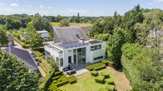 Deze ultra-moderne, energiezuinige villa (636 m² bewoonbare oppervlakte) heeft een strakke, witte kubusstructuur met metershoge glaswanden. Het pand beschikt over een EPC B-label, vloerverwarming (Viessmann), domotica, 24 zonnepanelen, leveren in totaal 9,8 kWp en een 12 kWh thuisbatterij.<br /><br />Gelegen op een perceel van ruim 20 are aan de Oude Baan in Essen. De tuin grenst aan agrarische velden, wat rust en privacy garandeert. Steden als Antwerpen en Breda liggen op 20 tot 30 minuten rijden. Natuurgebied de Kalmthoutse Heide bevindt zich dichtbij.<br /><br />Indeling:<br /><br />Gelijkvloers: Lichtrijke leefruimtes met een designhaard, een thuiskantoor met maatwerkkasten en een high-end leefkeuken met een groot werkeiland en luxe inbouwapparatuur.<br /><br />Verdiepingen: De eerste verdieping biedt een master bedroom met ensuite badkamer, plus twee slaapkamers en een tweede badkamer. De tweede verdieping telt nog twee slaapkamers en een derde badkamer.<br /><br />Kelder & Tuin: Een volledig onderkelderde ruimte, 200 m² aan casco ruimte (voor fitness, bioscoop, etc.). Er is alsook een inpandige garage voor 2 wagens. De strak aangelegde tuin heeft grote natuursteenterrassen en een beregeningsinstallatie.<br /><br />Bestuursmaatregelen in het maatregelenregister: nee