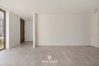 In het rustige, maar vlot bereikbare Leopoldsburg wacht een nieuwbouwwoning die comfort en functionaliteit combineert in een hedendaagse vormgeving. Deze woning biedt een ideale thuisbasis voor wie op zoek is naar kwaliteit, ruimte en een goede ligging, met alle voorzieningen binnen handbereik.<br />De halfopen bebouwing werd opgetrokken in 2025 en bevindt zich in een volledig nieuwe staat. Dankzij een bewoonbare oppervlakte van 144,44 m², verdeeld over twee volwaardige bouwlagen, geniet je hier van een goed doordachte indeling en een eigentijdse afwerking. De woning is voorzien van een carport en heeft een open en luchtige uitstraling.<br /><br />Op de gelijkvloerse verdieping vormt de leefruimte van 23,35 m² het centrale punt van het huis. Aansluitend bevindt zich een ruime eetruimte van 14,17 m², met directe verbinding naar de open keuken van 10,32 m². Samen vormen deze ruimtes een vloeiende leefomgeving waar koken, eten en ontspannen harmonieus samenkomen. Een schuifraam geeft uit op het terras, wat zorgt voor een natuurlijke lichtinval en een mooie connectie met buiten. Verder bevinden zich op deze verdieping een inkomhal van 4,30 m², een praktische berging van 3,52 m² en een gastentoilet van 1,53 m². Alles is logisch ingedeeld met oog voor dagelijks comfort.<br /><br />De eerste verdieping telt drie slaapkamers met oppervlaktes van respectievelijk 14,02 m², 12,38 m² en 9,98 m². Deze ruimtes bieden volop mogelijkheden voor een masterbedroom, kinderkamers of een thuiskantoor. De nachthal van 7,73 m² verbindt alle ruimtes efficiënt met elkaar. Daarnaast vind je op deze verdieping een aparte badkamer van 4,45 m² en een afzonderlijk toilet van 1,48 m². Ook werd er aan extra opbergruimte gedacht dankzij een berging van 4,47 m².<br /><br />Het perceel van 291 m² is zuidoostelijk georiënteerd. Dat betekent genieten van ochtend- en middagzon in de tuin. Een ideale ligging voor wie graag ontbijt in het zonnetje of een rustige middag op het terras waardeert. De oriëntatie laat bovendien mooie tuinplannen toe, zoals een loungehoek, moestuin of speelruimte.<br />Andere kenmerken zoals domotica of ventilatiesystemen werden niet vermeld, dus deze worden hier niet besproken.<br /><br />De woning bevindt zich op slechts 200 meter van scholen, ideaal voor jonge gezinnen. Ook het station ligt op amper 650 meter, wat zorgt voor een vlotte verbinding met andere steden. Met de snelwegen op minder dan 10 km afstand ben je bovendien goed ontsloten richting omliggende gemeenten. Voor wie graag ontspant, shopt of uit eten gaat: het centrum met winkels, restaurants en vrijetijdsopties ligt op slechts 1 km. <br /><br />Bovendien biedt deze woning een voordelig fiscaal voordeel: de grondwaarde bedraagt € 80 000 (12% registratierechten), terwijl de constructiewaarde van € 269 500 onder het 6 % btw-tarief valt.<br /><br />Deze nieuwbouwwoning in Leopoldsburg combineert een doordacht ontwerp met een praktische ligging en moderne woonkwaliteit. Maak vandaag nog een afspraak voor een persoonlijke rondleiding. Contacteer ons via 011 255 155. Bron bewoonbare oppervlakte: EPC – verslag.