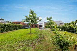 <p><strong>Ruime woning met multifunctionele studio</strong></p>
<p>In een <strong>rustige en aangename woonwijk</strong> te <strong>Vlimmeren</strong> bevindt zich deze verrassend ruime woning boordevol mogelijkheden voor <strong>grote gezinnen</strong>, <strong>thuiswerkers</strong> of wie op zoek is naar een combinatie van wonen, werken en ontspannen onder één dak.</p>
<p>De woning onderscheidt zich door haar <strong>royale leefruimtes</strong> en de aanwezigheid van een <strong>volledig aparte studio met eigen ingang</strong>. Deze multifunctionele ruimte biedt tal van mogelijkheden en kan perfect ingericht worden als <strong>zorgwoning</strong>, <strong>praktijkruimte voor een vrij beroep</strong>, <strong>kantoor</strong>, <strong>hobbyruimte</strong>, <strong>gastenverblijf</strong> of als woonunit voor een inwonend familielid. Dankzij de verbinding via de <strong>ruime garage</strong> blijven beide delen van de woning bovendien praktisch met elkaar verbonden.</p>
<p>Bij het betreden van de hoofdwoning komt u terecht in een <strong>ruime inkomhal</strong>, die toegang biedt tot de verschillende leefruimtes. De <strong>lichtrijke woonkamer</strong> vormt samen met de <strong>royale leefkeuken met kookeiland</strong> het hart van de woning. Aansluitend bevinden zich een bijkeuken en een <strong>speelkamer</strong>, die eveneens perfect kan dienen als bureau of hobbykamer.</p>
<p>Op de verdieping bevinden zich twee bijzonder ruime slaapkamers, waaronder een <strong>master bedroom</strong>, aangevuld met een <strong>grote dressing/inloopkast</strong>, een badkamer en een apart toilet. De extra leefruimte op deze verdieping biedt bovendien de mogelijkheid om, mits enkele beperkte aanpassingen, een <strong>volwaardige derde slaapkamer</strong> te creëren.</p>
<p>De studio beschikt over een eigen inkomhal, een aangename leefruimte met <strong>open keuken</strong>, een slaapkamer, bergruimte, een badkamer en een apart toilet. Hierdoor kan deze ruimte volledig zelfstandig functioneren en biedt ze maximale flexibiliteit voor diverse woon- of beroepsdoeleinden.</p>
<p>Ook buiten heeft deze woning heel wat te bieden. De <strong>volledig omheinde tuin</strong> garandeert optimale privacy en vormt een heerlijke plek om te ontspannen. Het <strong>zwembad</strong> zorgt voor een extra vleugje luxe en vakantiegevoel, terwijl de ruime, dubbele garage voldoende plaats biedt voor voertuigen, fietsen en extra opslagruimte.</p>
<p>Een eigendom dat dankzij haar <strong>ruimte</strong>, <strong>veelzijdigheid</strong> en <strong>uitstekende indeling</strong> perfect inspeelt op de woonnoden van vandaag en morgen. Een unieke opportuniteit voor wie op zoek is naar een woning met net dat beetje meer.</p>