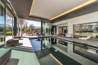 In een residentiële buurt te Sint-Idesbald (Koksijde), grenzend aan het natuurreservaat de Noordduinen vinden we deze prachtige villa te koop. De villa is gelegen op 2045m² en heeft een bewoonbare oppervlakte van maar liefst 615 m². Het gebruik van de meest hoogstaande afwerkingsmaterialen en het riante binnenzwembad garanderen in deze woning een gevoel van luxe en modern comfort. De woning werd in 1994 gebouwd en werd in 2009 grondig gerenoveerd. Het binnenzwembad werd in 2009 tevens volledig nieuw gebouwd.INDELING:> Gelijkvloers:- riante inkomhal in blauwsteen;- ruime leefruimte met open haard en bar. Vanuit deze leefruimte is er toegang tot het hypermoderne binnenzwembad (chloorvrij) voorzien van alle details (jet stream, domotica, lichthemel, ingebouwde anti-condens installatie, automatische gordijnen en zelfs een ingebouwd scherm met projector). Achterliggend is een infrarood-sauna met douche aanwezig;- volledig geïnstalleerde keuken met aanpalende berging en toegang tot de ruime garage;- bureauruimte met wasruimte;> Eerste verdieping:- master bedroom met en-suite badkamer voorzien van inloopdouche, dubbele lavabo met wasmeubel en tal van ingemaakte kasten en dressing. Aan de master bedroom grenst een aangenaam zonnig terras;- 2 slaapkamers;- badkamer met douche en lavabo met wasmeubel;> Ondergrondse verdieping:- bureauruimte; slaapkamer met douchekamer (met natuurlijk licht); geklimatiseerde wijnkelder; sportruimte; polyvalente ruimte; technisch lokaal;Verder beschikt de woning over een imposante oprijlaan die bereikt wordt via de automatische toegangspoort. De ruime tuin met volledig aangelegd terras is volledig zuid gericht en biedt een oase van rust. De villa is bovendien energiezuinig met een EPC van 131 kWh/ (m² jaar). De woning wordt verwarmd via een combinatie van 2 warmtepompen en mazoutketel. Er zijn bovendien 36 zonnepanelen aanwezig (geïnstalleerd in 2024).Interesse in deze villa te koop in Sint-Idesbald (Koksijde)? Ervaar zelf deze unieke woning en neem contact op met de dossierverantwoordelijke: Ellen Vandenbussche - 0474 49 47 89.