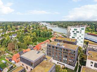 Op de 4e verdieping van het gerenommeerde woonproject Het Kanaal in Wijnegem bevindt zich dit bijzonder lichtrijke appartement met een bewoonbare oppervlakte van ca. 148 m² en een ruim overdekt terras van ca. 32 m². De combinatie van royale raampartijen, een plafondhoogte van bijna drie meter en een hoogwaardige materiaalkeuze zorgt voor een open en verfijnde woonbeleving.<br /><br />Het is mogelijk om hier indien gewenst meerdere slaapkamers te creëren.<br /><br />Het Kanaal vormt een uitzonderlijke woonomgeving waar industrieel erfgoed, hedendaagse architectuur, kunst en landschap samenkomen volgens de visie van Axel Vervoordt. De ligging aan het Albertkanaal biedt een bijzondere setting, terwijl Antwerpen, Schilde en de omliggende gemeenten vlot bereikbaar blijven.<br /><br />Indeling:<br />Het appartement is bereikbaar via de lift en opent in een ruime private inkomhal met vestiaire en geïntegreerde kastenwand. Natuursteen en maatwerk zetten meteen de toon. Aansluitend bevindt zich een afzonderlijk gastentoilet.<br /><br />De royale leefruimte van ca. 50 m² is afgewerkt met parket en wordt aan verschillende zijden omgeven door grote glaspartijen. Hierdoor geniet het interieur van een overvloed aan natuurlijk licht en mooie zichten op de omgeving. Een groot schuifraam geeft rechtstreeks toegang tot het overdekte terras van ca. 32 m², dat een aangename uitbreiding vormt van de woonruimte.<br /><br />Aansluitend bevinden zich de eetkamer van ca. 20 m² en de volledig ingerichte keuken van eveneens ca. 20 m². De keuken is uitgevoerd op natuursteen en voorzien van kwalitatieve inbouwtoestellen, waaronder toestellen van Miele, AEG en Novy.<br /><br />Een polyvalente ruimte van ca. 16 m², momenteel ingericht als dressing, vormt de overgang naar het private slaapgedeelte. De slaapkamer van ca. 16 m² beschikt over parketvloer en toegang tot een balkon.<br /><br />De ruime badkamer van ca. 13 m² is uitgevoerd in Carrara-marmer en voorzien van een vrijstaand ligbad, inloopdouche, dubbel lavabomeubel, handdoekradiator en afzonderlijk toilet. Verder beschikt het appartement over een praktische wasplaats met uitgietbak en technische voorzieningen.<br /><br />Bijzonderheden:<br />- Overdekt terras van ca. 32 m² met zicht op kanaal<br />- Royale plafondhoogte van ca. 2,92 m<br />- Uitzonderlijk veel natuurlijke lichtinval dankzij de grote raampartijen<br />- Royale leefruimte van ca. 50 m²<br />- Polyvalente ruimte, momenteel ingericht als dressing<br />- Lift aanwezig<br />- 2 ondergrondse autostaanplaatsen op niveau -1<br />- Vanuit garage met lift direct toegang tot app<br />- Automatische toegangspoort en videofoon<br />- EPC-label A, 82 kWh/(m² jaar)<br /><br />Unieke ligging binnen Het Kanaal, het internationaal gerenommeerde woon- en kunstproject van Axel Vervoordt