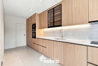 <strong>Het bezoekmoment gaat door op zaterdag 19 september 2026 (enkel op afspraak).</strong><br /><br />Luxueus gerenoveerd appartement in de groene en rustige residentie Ogierlande, waar comfort, kwaliteit en een verfijnde afwerking mooi samenkomen.<br /><br />Dit stijlvolle appartement (EPC-label B) combineert ruimte, natuurlijk licht en energiezuinig wonen met een hoogwaardige afwerking. Vanuit het zonnige terras geniet u van een aangenaam uitzicht op de zorgvuldig aangelegde gemeenschappelijke tuin, waar rust en groen centraal staan.<br /><br />Doorheen het appartement werd veel aandacht besteed aan materialen, details en een harmonieuze afwerking. De wanden en maatkasten werden uitgevoerd in een verfijnde Claystuc-techniek. De zachte textuur en natuurlijke kleurnuances geven het interieur een warme en rustige uitstraling.<br /><br />In de inkomhal zorgt een sensor voor de automatische sfeerverlichting, die discreet in de wand is geïntegreerd. Een verfijnd detail dat mooi aansluit bij de rustige uitstraling van het interieur. De lichtrijke leefruimte beschikt over een hoogwaardige parketvloer van Woodstoxx, stijlvolle maatkasten en een rechtstreekse toegang tot het zonnige terras.<br />De volledig geïnstalleerde keuken is uitgerust met kwalitatieve Siemens-toestellen en sluit mooi aan bij de uitstraling van de leefruimte. Aansluitend bevindt zich een praktische berging/wasruimte, voorzien van een waterontharder.<br />Verder beschikt het appartement over een afzonderlijk gastentoilet, twee ruime slaapkamers en een verzorgde badkamer met ligbad met douchefunctie en dubbele lavabo. Daarnaast is er een private kelderberging aanwezig.<br /><br />Ook op het vlak van comfort werd aan de nodige details gedacht. Aan de voorzijde zijn automatische rolluiken voorzien en aan de achterzijde zonnescreens. De temperatuur in het appartement kan bovendien vanop afstand worden geregeld.<br /><br />Een verzorgd en tijdloos appartement met een rustige uitstraling, kwalitatieve materialen en aandacht voor detail.<br /><br />Mogelijkheid tot aankoop van:<br />Ondergrondse garagebox met automatisch poort aan €30.000,-<br />Bovengrondse staanplaats bij te kopen aan €15.000,-<br /><br /><strong>Ook wild geworden van deze thuis?<br />Ontdek zelf de aangename sfeer, hoogwaardige afwerking en rustige ligging van dit appartement en plan vandaag nog uw bezoek.</strong>
