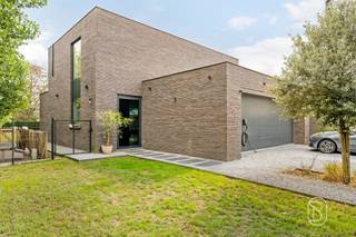 Deze prachtige moderne woning (2019) gelegen in Eke biedt een unieke combinatie van hedendaags design en energiezuinigheid. Met een bewoonbare oppervlakte van 208 m² en een grondoppervlakte van 670 m² beschikt deze woning over alles wat u nodig heeft om comfortabel te wonen.Welkom op de SALESDAY 02/10 met richtprijs 695.000€Het ontwerp is gekenmerkt door grote glazen elementen die optimale lichtinval garanderen en een naadloze verbinding creëren tussen binnen- en buitenruimte. De open plaatsing van ramen en deuren zorgt voor een lichte en uitnodigende sfeer door heel het huis.De woning beschikt over 3 slaapkamers die voorzien zijn van natuurlijk licht dankzij raampartijen met zicht op het omliggende groen. De open leefruimte combineert woonkamer, eetkamer en keuken in één grote, multifunctionele zone met veel bewegingsvrijheid. Dit concept is ideaal voor gezinnen en ondersteunt een moderne leefstijl.De moderne keuken is voorzien van hoogwaardige inbouwapparatuur en genoeg werkblad- en bergruimte. Het design met witte kasten en zwart accent-accenten straalt elegantie uit. De badkamer beschikt over een vrijstaand bad en een inloopdouche met grijs tegeltwerk, compleet met sanitair van topkwaliteit.Met een garage en ruim grind- en graspaden is parkeren geen probleem. De grote tuinoppervlakte biedt volop mogelijkheden voor ontspanning en recreatie. Ieder detail van deze woning is zorgvuldig afgewerkt met premium materialen. De combinatie van warme houttinten, donkere tegelvloeren en neutrale muurtinten creëert een sfeervol en tijdloos interieur. TROEVEN- Het E-peil is opgemaakt van voor zonnepanelen en thuislaadbatterij zijn geplaatst- gelegen aan een fietssnelweg- airco bijgeplaatst in 2022- gezellige gashaard- voorzieningen klaar voor badkamer 2