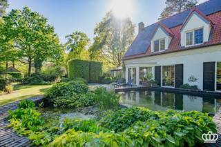 <p><span>Luxueuze villa opgetrokken in een tijdloze Knokkestijl, gelegen op een schitterende locatie: in een bosrijke, residentiële omgeving nabij het centrum van Heide en op wandelafstand van de Royal Antwerp Golf, op een oost gericht perceel van ca. 7.361 m², voorzien van o.a. 6 slaapkamers, 4 badkamers, paddock met stallen, mooi aangelegde vijver, prachtig aangelegde tuin en verwarmd zwembad met poolhouse. </span></p><p><span> </span></p><p><span>Gelijkvloers</span></p><p><span>Ruime inkomhal voorzien van een vestiaire en een gastentoilet met handenwasser. </span></p><p><span>Via een glazen deur betreedt u de royale, lichtrijke leefruimte op eiken parket, ingedeeld in een gezellige zithoek met sfeervolle houtkachel, een eetgedeelte en een orangerie op natuursteen. Vanuit de orangerie (voorzien van automatische zonnewering) geniet u van een idyllisch uitzicht op de aangelegde tuin en de aangrenzende paardenweide.</span></p><p><span>Aansluitend bevindt zich de leefkeuken uitgerust met een aanrecht in blauwe hardsteen voorzien van een Amerikaanse koelkast, vaatwasser en een kwalitatief 4-pits La Cornue-fornuis voorzien van: twee ovens (1 gas en 1 elektrisch), friteuse, teppanyaki-plaat en wokvuur. Ook hier is een aparte eethoek voorzien met zicht op de tuin.</span></p><p><span>De praktische bijkeuken/wasplaats beschikt over aansluitingen voor wasmachine en droogkast. Vanuit de bijkeuken is er toegang tot de ruime, dubbele inpandige garage met automatische poorten en ingemaakte kasten.</span></p><p><span>Verder is er, grenzend aan de inkomhal, een bureelruimte op eiken parket met ingemaakte kasten.</span></p><p><span> </span></p><p><span>Eerste</span><span> </span><span>verdieping</span></p><p><span>Via een open trap heeft u toegang tot de nachthal voorzien van ingemaakte kasten en de slaapkamers, allen op parket.</span></p><p><span>De masterslaapkamer is voorzien van een ensuite dressing en ensuite badkamer. Verder bevindt zich hier een beamer met uitrolbaar scherm en surround systeem én airco.</span></p><p><span>De tweede slaapkamer is uitgerust met een bureel en een ensuite badkamer. Daarnaast bevindt zich een derde slaapkamer met ingemaakte kasten. Verder is er een aparte fitnessruimte, die ook perfect dienst kan doen als vierde slaapkamer. Op deze verdieping bevindt zich nog een apart toilet en een aparte badkamer met stoomdouche. Vervolgens is er nog een vijfde slaapkamer.</span></p><p><span> </span></p><p><span>Zolder</span></p><p><span>Een vaste trap leidt naar een bijkomende zesde slaapkamer. Op deze verdieping bevindt zich ook nog een bergruimte en een extra kamer die naar wens ingericht kan worden.</span></p><p><span> </span></p><p><span>Kelder</span></p><p><span>Onder de villa is een droge kruipruimte aanwezig.</span></p><p><span> </span></p><p><span>Tuin</span></p><p><span>De villa is gelegen op een oost gericht perceel van ca. 7.361 m². Via een automatische houten poort met mooie oprijlaan heeft u toegang tot het perceel. Aan de voorzijde bevindt zich een mooi aangelegde tuin en een oprit die leidt naar de dubbele inpandige garage en carport.</span></p><p><span>Achteraan bevindt zich een verhoogd open terras, 2 vijvers waarvan 1 koivijver, een paddock of weide met paardenstallen en een verwarmde zadelkamer. tuin en paddock volledige gedraineerd, verlicht en eigen watervoorziening.</span></p><p><span>Verder is er een verwarmd zwembad met een volledig uitgerust poolhouse, voorzien van een overdekt terras, panorama sauna, bar, sanitaire voorzieningen, zithoek, muziekinstallatie, technische ruimte en een bergzolder. De tuin is voorzien van een automatisch beregeningssysteem. </span></p><p><span> </span></p><p><span>Bijzonderheden</span></p><p><span>- Gelegen op een gegeerde locatie: in een bosrijke, residentiële omgeving, nabij het centrum van Heide en op wandelafstand van de Royal Antwerp Golf </span></p><p><span>- Energiezuinig dankzij 24 nieuwe zonnepanelen, recent nieuwe ramen en nieuw dak 2025</span></p><p><span>- Mogelijkheid tot kantoor aan huis, inwonend personeel,…</span></p><p><span>- Uitzonderlijk breed perceel </span></p><p><span>- Ideaal voor paardenliefhebbers dankzij paddock en stallen </span></p><p><span>- Verwarmd zwembad met poolhouse</span></p><p><span>- Centraal muzieksysteem</span></p><p><span>- Prachtig aangelegde tuin met oost gerichte oriëntatie en verschillende vijvers </span></p><p><span>- Dubbele inpandige garage</span></p><p><span>- Waterontharder</span></p><p><span>- Elektriciteit conform</span></p><p><span>- Asbestveilig</span></p><p><span> </span></p>