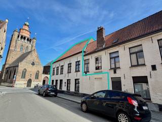 Deze karaktervolle HOEKWONING met TUIN en aanpalende GARAGE is gelegen in het gegeerde Sint-Annakwartier, in het historische hart van Brugge. Het pand kent een rijke bouwgeschiedenis, met onder meer de jaarankers 1681, en deed vroeger dienst als apotheek.
De te renoveren woning omvat een inkomhal met toilet, een grote polyvalente ruimte die dienst kan doen als praktijk of kantoor voor een vrij beroep., een ruime leefruimte met eet- en zithoek, keuken met toegang tot terras en tuin, vier slaapkamers en een badkamer. De royale zolder onder de indrukwekkende dakstructuur biedt heel wat mogelijkheden en geniet bovendien van een mooi zicht op de Jeruzalemkerk.
De aangename tuin is een absolute troef in deze historische stadsomgeving. De woning leent zich zowel tot ruim wonen als tot wonen en werken.
EPC-label D, bouwkundig erfgoed.
De aanpalende garage beschikt op het gelijkvloers over een ruime garage en omvat op de eerste verdieping nog twee polyvalente ruimtes. Onder het dak bevindt zich bovendien een kruipzolder. Ook de garage is opgenomen als bouwkundig erfgoed.
Er bestaat tevens de mogelijkheid om de aanpalende woning met koer, Molenmeers 72, mee aan te kopen.