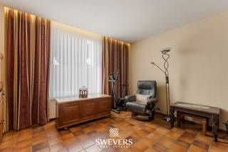 Voor meer info en foto’s, surf naar www.swevers.be – In de Sint-Albanusstraat 15 in Riemst vindt u deze halfopen bebouwing uit 1931 met een bewoonbare oppervlakte van ca. 120 m² op een perceel van 335 m². De woning is op te frissen, wat heel wat mogelijkheden biedt om ze volledig naar eigen smaak en volgens hedendaagse normen in te richten. Via de inkomhal komt u in de woonkamer van ca. 27 m², met aansluitend de eetkamer en de compacte, functionele keuken van ca. 4,80 m². Op het gelijkvloers zijn verder nog een badkamer, apart toilet, berging, een ruime werkplaats met drijfkracht aanwezig, ideaal als hobbyruimte, atelier of extra opslag. Op de eerste verdieping geeft de nachthal toegang tot 3 slaapkamers van ca. 7,50 m², 10,31 m² en 10,52 m². Daarnaast beschikt de woning over een kelder van ca. 8,48 m² en een zolder van ca. 30 m², wat extra bergruimte en bijkomend potentieel biedt. Een grote troef is de ruime garage van ongeveer 50 m², goed voor 2 wagens en extra stockageruimte. Ook de ligging is praktisch: winkels liggen op amper 700 meter, openbaar vervoer op 120 meter en scholen op 650 meter. Ontspanning vindt u op 450 meter en de snelweg bereikt u op 5,9 km. Deze woning vormt een interessante kans voor wie op zoek is naar een pand met karakter, ruimte en renovatiemogelijkheden op een vlot bereikbare locatie. Voor meer informatie, bel 011 255 155. Bron bewoonbare oppervlakte: EPC – verslag.