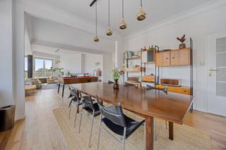 <p><strong>Wonen op een toplocatie met ruimte in overvloed<br /><br /></strong>Dit ruime appartement bevindt zich op een bijzonder aantrekkelijke locatie, op de hoek van de Bosmanslei en de Jan Van Rijswijcklaan. Ook qua bereikbaarheid zit je uitstekend: de tram stopt vlak voor de deur en zowel het stadscentrum als de A12 en de belangrijkste autosnelwegen zijn vlot bereikbaar.<br /><br />Bij binnenkomst springt meteen de karaktervolle uitstraling van Résidence Le Zodiaque in het oog. Het modernistische gebouw dateert uit 1957 en ademt nog steeds een typische retrostijl uit de jaren 50. Het goed onderhouden complex telt zeven verdiepingen, waarbij dit appartement zich op de vijfde verdieping bevindt.<br /><br />De woning biedt bijzonder veel mogelijkheden. In totaal zijn er vijf slaapkamers, drie badkamers en vijf toiletten. Daardoor is er voldoende plaats voor een groot gezin, een samengesteld gezin of een cohousingproject. De vijfde kamer bevindt zich naast de leefruimte en wordt momenteel gebruikt als bureau, maar kan eenvoudig opnieuw als slaapkamer worden ingericht.<br /><br />De keuken, die toegang geeft tot een terras, en de badkamers zijn meteen bruikbaar, al kunnen ze op termijn wel een moderne update gebruiken. Een bijkomend voordeel is het gunstige EPC-label B.<br /><br />De absolute blikvanger van het appartement is zonder twijfel de woonkamer. De originele parketvloer uit 1957 geeft de ruimte veel karakter, terwijl de grote ramen zorgen voor een overvloed aan natuurlijk licht. Het panoramische uitzicht over de Singel en de stad maakt het geheel extra bijzonder.<br /><br />Dankzij de hoekligging en de indeling rond de centrale liftkern komt er bovendien in vrijwel elke kamer veel daglicht en frisse lucht binnen. Het resultaat is een aangenaam en ruimtelijk appartement met een unieke combinatie van karakter, licht en mogelijkheden.<br /><br />Er is een privatieve kelderberging bij het appartement.<br /><br />Als extra optie kan er een dubbele garagebox worden aangekocht waarbij ook de oprit privatief kan gebruikt worden voor 3 wagens. De vraagprijs hiervoor bedraagt €95.000</p>
<p> </p>