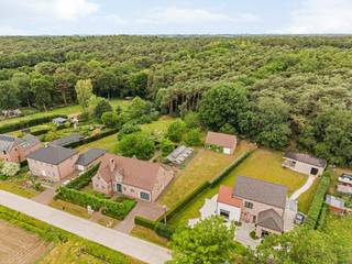 Deze ruime gezinswoning biedt zowel voor -als achteraan een groen uitzicht op bos -en landbouwgebied waardoor het hier zeer rustig vertoeven is.<br />De eigendom biedt zowel binnen als buiten zeer veel ruimte met zijn 4 slaapkamers, 2 badkamers, ruime keuken, wasplaats, inpandige garage, onderkeldering en bijgebouw van +/- 100m² achter de woning. <br />Het is eveneens mogelijk de woning volledig gelijkvloers te bewonen door de aanwezigheid van een gelijkvloerse bureau/slaapkamer en badkamer. <br /><br />We betreden deze villa via de zeer open inkomhal die onmiddellijk toegang biedt tot de gelijkvloerse bureau/slaapkamer.<br />Deze goed ingedeelde woning beschikt verder op de gelijkvloerse verdieping over een zeer ruime L-vormige woonkamer die voorzien is van vele ramen en dus veel natuurlijk licht. Deze sluit aan op de functionele keuken die verder voorzien is van wasplaats met ingemaakte kasten en douche, bergruimte, apart toilet en inpandige garage met automatische poort. <br /><br />Op de verdieping vinden we vier volwaardige slaapkamers terug. Eén hiervan kan eventueel nog opgedeeld worden in 2 aparte slaapkamers. De badkamer is eveneens zeer ruim voorzien en beschikt over dubbele lavabo, douche en ligbad. Verder is er een extra bergruimte aanwezig op deze verdieping.<br />De zolder is bereikbaar via een vlizotrap. Deze is mogelijks nog verder af te werken tot extra bewoonbare ruimte.<br /><br />Een absolute troef is de tuin die beschikt over een overdekt terras en het vrijstaande bijgebouw van maar liefst +/- 100 m² en voorzien is van een poort. Deze is ideaal als werkplaats, opslagruimte, atelier, hobbyruimte of voor wie een zelfstandige activiteit wil combineren met wonen.<br /><br />Bijzonderheden:<br />- Unieke locatie met zowel voor -als achteraan groen uitzicht<br />- Mogelijkheid extra bosgrond bij te kopen<br />- Bijgebouw van +/- 100m²<br />- Zeer ruime bewoonbare oppervlakte waardoor de woning dienst kan doen voor verschillende doeleinden<br />- Geboorde grondwaterput<br />- Alarm<br />- Rolluiken