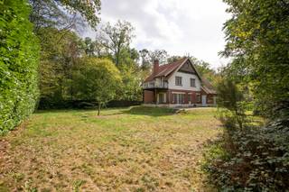 Achter de gevel met de naam ‘Les Hirondelles’ ontdek je een woning waar het karakter van vroeger nog volop aanwezig is. Originele houten deuren, plankenvloeren en grote ramen geven de ruimtes hun warme uitstraling en laten het groen rondom mee deel uitmaken van het interieur.De ruime inkomhal met kachel zet meteen de toon. Van hieruit kom je in de lichte leefruimte met houten vloer en haard. De keuken heeft een opvallende authentieke tegelvloer en geeft toegang naar buiten. Aansluitend ligt de garage met bergruimte. De woning is bovendien volledig onderkelderd.Op de tussenverdieping ligt een slaapkamer met ingemaakte kasten. De eerste verdieping biedt een masterbedroom met toegang tot het balkon, een aangrenzende ruimte die je als dressing met bad kunt inrichten, een derde slaapkamer en een badkamer. Helemaal boven is er nog ruimte voor een vierde slaapkamer, een bureau of een andere invulling die bij je past.‘Les Hirondelles’ is een huis voor wie valt voor authentieke details en graag een plek naar eigen smaak verder vormgeeft.De weergegeven oppervlakte werd overgenomen van het EPC-attest en is louter informatief.