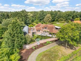 Deze authentieke villa straalt warmte en karakter uit. Afgewerkt met duurzame materialen en behoud van originele elementen, biedt deze villa een unieke combinatie van charme en comfort. <br />De leefruimtes kijken uit op een prachtig aangelegde tuin met vijver, een oase van rust. <br />Binnen zorgt de privé wellnessruimte met binnenzwembad voor een extra gevoel van luxe. <br />Een ideale keuze voor wie op zoek naar ruimte, rust en een stijlvolle thuis met een ziel. <br /><br />Deze villa ligt in de rustige en groene Monninxstraat te Hasselt. U woont hier residentieel, met vlotte verbinding naar winkels, scholen, het centrum en de autosnelweg. Ideaal voor wie houdt van comfort en bereikbaarheid in een serene omgeving<br /><br />=> Gelijkvloers<br />- Ruime inkomhal met vestiaireruimte<br />- Glazen deur naar het leefgedeelte<br />- Gezellige zithoek met open haard op hout<br />- Authentieke houten balken structuur<br />- Eethoek met zicht op de tuin<br />- Praktijkruimte, ideaal voor zelfstandigen in bijberoep<br />- Moderne, luxueuze keuken met veel opbergruimte en ruimte om te dineren<br />- Rechtstreeks toegang tot het terras vanuit de keuken<br />- Wasplaats met ingebouwde kastenwand<br />- Aparte praktische berging<br />- Wellnessruimte met verwarmd binnenzwembad, stoomdouche en sauna<br />- Aparte berging en toilet in de wellnessruimte<br />- Ingerichte kleedruimte<br /><br />=> Verdieping<br />- Eiken trap naar de verdieping<br />- Overloop met zicht op de woonkamer<br />- Master bedroom met ingebouwde kastenwand<br />- Ensuite badkamer met ligbad, douche en dubbele lavabo in stijlvol badkamermeubel<br />- Drie ruime slaapkamers, elk voorzien van een vaste kastenwand<br />- Tweede badkamer met ligbad, douche en enkele lavabo in badkamermeubel<br /><br />= Tuin<br />- Een royaal perceel van 48a 75ca <br />- Prachtige vijver in de parkachtige tuin <br />- Oase van rust en privacy<br />- Overdekt terras aan de voor-en achterzijde van de woning<br />- Buitenkeuken met barbecue, ideaal voor gezellige zomeravonden<br />- Zwemvijver aan de zuidkant van het perceel <br /><br />=> Indeling<br />- Gelijkvloers: inkomhal, woonkamer, keuken, praktijkruimte, wasplaats, berging, wellnessruimte met berging en kleedruimte<br />- Verdieping: overloop, master bedroom, ensuite badkamer, drie slaapkamers, tweede badkamer