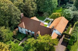 <p><span>Deze bijzonder ruime villa in Long Island-stijl is gelegen aan de Frilinglei, één van de meest gegeerde locaties van Brasschaat-Vriesdonk op een perceel van ca. 3.182 m²</span></p><p><span> </span></p><p><span>Indeling</span><span>: U betreedt de villa middels de ruime centrale inkomhal met vestiaire en gastentoilet. De natuurstenen vloer en brede zichtlijnen geven onmiddellijk een indruk van de royale volumes van de woning. Aan de voorzijde bevindt zich een afzonderlijke tv-kamer met maatwerkmeubilair. Aansluitend ligt de ruime woonkamer, welke werd ingericht met verschillende zitgedeeltes en een sfeervolle open haard. Grote raampartijen en schuifdeuren zorgen voor veel natuurlijk licht en geven rechtstreeks toegang tot de terrassen en tuin. De aansluitende eetkamer vormt een mooie verbinding tussen de woonkamer, ontbijtkamer en keuken. Ook hier zorgen de raampartijen voor een aangename relatie met het omliggende groen. De royale keuken werd ingericht met veel kastruimte en diverse inbouwtoestellen. Een afzonderlijke ontbijtkamer biedt ruimte voor dagelijks tafelen en geeft uit op het terras. Aansluitend bevinden zich een praktische bijkeuken en wasplaats.</span></p><p><span> </span></p><p><span>Inpandig zwembad</span><span>: Een bijzondere troef is het inpandige zwembad met grote raampartijen naar de tuin en vormt een private ontspanningsomgeving binnen de woning. Het inpandige zwembad werd nog niet gerenoveerd doch is functioneel. De afzonderlijke technische ruimte bevindt zich direct naast het zwembad en beschikt ook over een aparte toegangsdeur voor onderhoudspersoneel.</span></p><p><span> </span></p><p><span>Garages</span><span>: De villa beschikt over drie inpandige garages en een ruime, volledig verharde oprit met parkeergelegenheid voor meerdere wagens. Vanuit de garage heeft u toegang tot de kelder.</span></p><p><span> </span></p><p><span>Kelder</span><span>: De woning beschikt over een praktische kelder met bergruimte en wijnkelder. De villa is verder volledig voorzien van kruipruimte.</span></p><p><span> </span></p><p><span>Eerste verdieping</span><span>: De centrale trap leidt naar de ruime nachthal op de eerste verdieping. De royale mastersuite vormt een afzonderlijk en comfortabel geheel met een ruime slaapkamer, eigen dressing en een luxueus vernieuwde badkamer, stijlvol afgewerkt en ingericht met een vrijstaand ligbad, ruime inloopdouche, dubbele wastafel en toilet. Tevens een logeerkamer of bijkomende slaapkamer met eveneens een badkamer. Daarnaast bevinden zich op deze verdieping nog drie volwaardige slaapkamers en drie badkamers. De kamers beschikken over mooie volumes, natuurlijk lichtinval en diverse bergmogelijkheden. </span></p><p><span> </span></p><p><span>Tuin en buitenruimtes</span><span>: De villa wordt omgeven door een volwassen en bijzonder private tuin met uitgebreide tuinverlichting. De automatische toegangspoort, hoge hagen en volwassen bomen creëren een groen kader rondom de woning en waarborgen een hoge mate van rust en privacy. De tuin werd voorzien van een automatisch beregeningssysteem welke is aangesloten op een geboorde put van ca 70 meter diep. Aan de achterzijde zijn royale terrassen welke rechtstreeks aansluiten op de verschillende leefruimtes. De ruime oprit aan de zijkant van het eigendom biedt een discrete toegang tot de garages en bijkomende parkeergelegenheid.</span></p><p><span> </span></p><p><span>Bijzonderheden</span><span>: Deze villa werd gebouwd in 1988 door Vlassak-Verhulst met hoogwaardige en duurzame materialen en gerenoveerd in 2022. De woning biedt u royale leefruimtes, vijf slaapkamers, zes badkamers, een inpandig zwembad en drie garages en onderscheidt zich door haar Long Island-architectuur, bijzonder royale woonoppervlakte en flexibele indeling. Recent werden reeds verschillende renovatie- en opfrissingswerken uitgevoerd waarbij onder meer de volledige elektrische installatie werd vernieuwd, een uitgebreid KNX-domoticasysteem werd voorzien voor de intelligente aansturing van de woning, nieuwe toegangspoort en garagepoorten en werden de houten vloeren opnieuw geschuurd. Deze villa is een bijzonder eigendom op één van de mooiste locaties van Brasschaat-Vriesdonk.</span></p><p><span> </span></p><p><span>Meer inlichtingen via ons kantoor.</span></p>