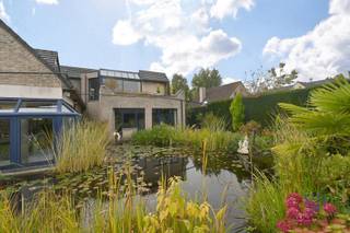 Dit bijzonder ruime en tijdloze pand biedt de unieke mogelijkheid om wonen en werken te combineren in een aangename, stijlvolle omgeving.<br /><br />Bij het betreden van het gebouw komt u terecht in een statige inkomhal die rechtstreeks aansluit op de balie en doorloopt naar de toonzaal en verkoopruimte. Deze open en representatieve zone vormt het kloppend hart van het gelijkvloers en creëert een professionele eerste indruk voor bezoekers en klanten.<br /><br />Verder zijn er meerdere afzonderlijke burelen voorzien, waaronder één kantoor met uitzicht op de achtergelegen vijver – een rustgevende plek die werken in een kalme, groene omgeving mogelijk maakt. Daarnaast is er een open landschapskantoor, een praktische kitchenette, een apart toilet en meerdere bergruimtes - werkruimtes aanwezig.<br /><br />Ook een les- of vergaderruimte maakt deel uit van het gelijkvloers, wat het pand uitermate geschikt maakt voor opleidingen, workshops of teamvergaderingen. Aan de zijkanten (links en rechts) bevinden zich in totaal vier garages, die samen met de parkeermogelijkheden aan de voorzijde én achterzijde van het gebouw zorgen voor een uitstekende bereikbaarheid. Ook een kelder is voorzien. <br /><br />Op de verdieping bevindt zich een riant penthouse waar het woongedeelte volledig tot zijn recht komt. Hier vindt u een ruime leefruimte, een uitgeruste keuken, vier comfortabele slaapkamers en een stijlvolle badkamer.<br />Als kers op de taart is er een wellnessruimte met spa-hoek en sauna, perfect om na een drukke werkdag volledig tot rust te komen. Zowel aan de voorzijde als aan de achterzijde van het gebouw bevinden zich ruime terrassen, ideaal om te genieten van de zon of het uitzicht op de tuin met vijver.<br /><br />Ook op de bovenverdieping is er meer dan voldoende bergruimte, dankzij de aanwezigheid van een atelier, een praktische opslagruimte en zolders aan beide kanten van het gebouw.<br /><br />De tuin is voorzien van o.a. een sierlijke vijver, een recente buitenberging met overkapping en carports voor meerdere wagens. De combinatie van functionaliteit, rust en ruimte maakt van dit pand een echte buitenkans.<br /><br />Bent u op zoek naar een ruim, veelzijdig eigendom waar wonen en werken in perfecte harmonie samengaan? Dan is dit pand precies wat u zoekt.