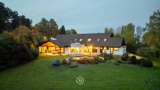 In het afgesloten en residentiële domein “Vlieringenpark” bevindt zich deze unieke villa, ontworpen in een verfijnde Scandinavische architectuurstijl en genietend van een prachtig, open vergezicht.<br /><br />De woning combineert een Scandinavisch design, natuurlijke materialen en functionaliteit en biedt bovendien tal van mogelijkheden, zoals het inrichten van een aparte studio voor een au pair of een bureau voor een vrij beroep.<br /><br />Indeling:<br />Gelijkvloers (0): Inkomhal met vestiaire en gastentoilet, ruime leefruimte met zithoek en eetplaats, volledig uitgeruste keuken met bijkeuken, veranda, masterbedroom met dressing en ensuite badkamer, wasplaats, berging en atelierruimte.<br />Verdieping (+1): mezzanine met bureauruimte, twee slaapkamers met ensuite badkamer, kinderkamer en extra opbergruimte.<br />Zolder (+2): opbergzolder.<br />Kelder (-1): wijnkelder en 3 ruime kelderruimtes.