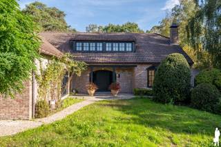 <strong>Karaktervolle villa op royaal groen domein van ca. 6.228 m² nabij het Zoerselbos<br /></strong><br /><strong>Op een prachtig groen en volledig afgesloten perceel van ca. 6.228 m², vlak bij het Zoerselbos, bevindt zich deze bijzonder ruime en uitstekend onderhouden villa. De woning werd in 2000 grondig gerenoveerd en uitgebreid en combineert royale leefruimtes met een sterke connectie met de tuin. Grote glaspartijen, veel privacy en een veelzijdige indeling zorgen voor een bijzonder aangename woonbeleving.</strong><br /><br /><strong>Gelijkvloerse verdieping</strong><br />
<ul>
<li>Ruime inkomhal met karaktervolle boogvormen, natuurstenen vloer, gastentoilet met handenwasser en afzonderlijke verstiaire;</li>
<li>Prachtige leefruimte op natuursteen met grote glaspartijen, dubbele schuiframen en een voormalige zitput, heden dichtgemaakt en geïntegreerd in de leefruimte, met een bijzonder mooi zicht op het terras en de tuin;</li>
<li>Royale leefkeuken in een vooruitgeschoven volume, waardoor het groen rondom volop beleefd wordt, met dubbele spoelbak en toestellen waaronder een AGA-fornuis, Smeg ingebouwde friteuse, Miele vaatwasser, Siemens oven en microgolfoven en een Liebherr koelkast en diepvriezer;</li>
<li>Praktische bijkeuken met ingemaakte kasten, spoelbak en toegang tot terras en tuin;</li>
<li>Twee ruime kamers op parket, ideaal als slaapkamer, bureau, speelkamer of afzonderlijke tv-kamer;</li>
<li>Inpandige garage met automatische poort;</li>
</ul>
<strong>Eerste verdieping</strong><br />
<ul>
<li>Nachthal met afzonderlijk toilet en handenwasser;</li>
<li>Hoofdslaapkamer op parket met toegang tot het dakterras en prachtig zicht over de tuin;</li>
<li>Badkamer met ligbad met jacuzzifunctie, douche, dubbele wastafel en bidet;</li>
<li>Drie bijkomende slaapkamers op parket;</li>
<li>Praktische opbergruimte onder de schuine dakvlakken;</li>
</ul>
<strong>Kelder</strong><br />
<ul>
<li>Kelderruimte met ingemaakte kasten met geïntegreerde koel- en diepvriesvoorzieningen;</li>
<li>Bijkomende bergmogelijkheden;</li>
</ul>
<strong>Tuin en buitenruimte</strong><br />
<ul>
<li>Uitzonderlijk ruime en prachtig aangelegde tuin met volwassen bomenbestand;</li>
<li>Uitgestrekte gazonzones, sierbomen, hagen en sfeervolle vijver;</li>
<li>Ruim terras en gedeeltelijk overdekt terras aansluitend op de leefruimtes;</li>
<li>Diepe zichtlijnen en een bijzonder gevoel van rust en privacy;</li>
<li>Chalet/gastenverblijf met badkamer, toilet, kitchenette en afzonderlijke recente verwarmingsketel;</li>
<li>Serre en tuinhuis met bijkomende opbergruimte en 3 carports;</li>
<li>Volledig omheind en afgesloten domein met automatische toegangspoort;</li>
<li>Robotmaaier</li>
</ul>
<strong>Algemeen</strong><br />
<ul>
<li>Woning grondig gerenoveerd en uitgebreid in 2000;</li>
<li>Elektrische installatie vernieuwd in 2004 (en conform);</li>
<li>Wateronthardingsinstallatie JUDO;</li>
<li>Verwarming op aardgas (deels) via vloerverwarming;</li>
<li>Parketvloeren recent opnieuw opgeschuurd;</li>
<li>Interieur en buitenschrijnwerk recent volledig opnieuw geschilderd;</li>
<li>Zeer verzorgde en uitstekend onderhouden eigendom;</li>
<li>Videofonie;</li>
<li>Veelzijdige indeling met mogelijkheden voor thuiswerk, hobby, gasten of bijkomende slaapkamers;</li>
<li>Bijzonder veel privacy dankzij de omvang en groene omkadering van het perceel;</li>
</ul>
<strong>Inclusief naastgelegen perceel</strong><br />Naast het hoofdeigendom bevindt zich een afzonderlijk perceel van ca. 1.520 m², inbegrepen in de vraagprijs. Op dit perceel bevindt zich momenteel een achterliggend atelier met carport.