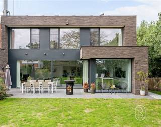 Deze prachtige moderne woning (2019) gelegen in Eke biedt een unieke combinatie van hedendaags design en energiezuinigheid. Met een bewoonbare oppervlakte van 208 m² en een grondoppervlakte van 670 m² beschikt deze woning over alles wat u nodig heeft om comfortabel te wonen.Welkom op de SALESDAY 02/10 met richtprijs 695.000€Het ontwerp is gekenmerkt door grote glazen elementen die optimale lichtinval garanderen en een naadloze verbinding creëren tussen binnen- en buitenruimte. De open plaatsing van ramen en deuren zorgt voor een lichte en uitnodigende sfeer door heel het huis.De woning beschikt over 3 slaapkamers die voorzien zijn van natuurlijk licht dankzij raampartijen met zicht op het omliggende groen. De open leefruimte combineert woonkamer, eetkamer en keuken in één grote, multifunctionele zone met veel bewegingsvrijheid. Dit concept is ideaal voor gezinnen en ondersteunt een moderne leefstijl.De moderne keuken is voorzien van hoogwaardige inbouwapparatuur en genoeg werkblad- en bergruimte. Het design met witte kasten en zwart accent-accenten straalt elegantie uit. De badkamer beschikt over een vrijstaand bad en een inloopdouche met grijs tegeltwerk, compleet met sanitair van topkwaliteit.Met een garage en ruim grind- en graspaden is parkeren geen probleem. De grote tuinoppervlakte biedt volop mogelijkheden voor ontspanning en recreatie. Ieder detail van deze woning is zorgvuldig afgewerkt met premium materialen. De combinatie van warme houttinten, donkere tegelvloeren en neutrale muurtinten creëert een sfeervol en tijdloos interieur. TROEVEN- Het E-peil is opgemaakt van voor zonnepanelen en thuislaadbatterij zijn geplaatst- gelegen aan een fietssnelweg- airco bijgeplaatst in 2022- gezellige gashaard- voorzieningen klaar voor badkamer 2