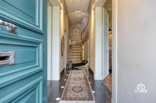 MAJESTUEUZE WONING MET KARAKTER EN ZUIDGERICHTE TUIN IN GIJZEGEMDeze karaktervolle en majestueuze woning is gelegen in Gijzegem, op een gunstige locatie tussen Aalst en Dendermonde. De woning werd doorheen de jaren met bijzonder veel zorg onderhouden en kwalitatief vernieuwd, waarbij de authentieke architecturale elementen en het karakter van het pand steeds werden gerespecteerd.Via de statige inkomhal, waar de hoge plafonds meteen in het oog springen, betreedt u de woning. Het gelijkvloers omvat een ingerichte keuken, een sfeervolle eetkamer en een ruime woonkamer met aansluitend een bureauruimte. De veranda biedt een prachtig zicht op het terras en de zorgvuldig aangelegde tuin. De aanbouw omvat een moderne badkamer, praktische berging en garage.Op de eerste verdieping bevinden zich drie volwaardige slaapkamers en een ingerichte badkamer. Een tussenverdieping biedt plaats aan een vierde slaapkamer. De woning beschikt bovendien over een volledig overzolderde zolderverdieping, waarvan de vloer werd geïsoleerd. De ruime, droge kelder is onderverdeeld in verschillende compartimenten en biedt heel wat praktische bergruimte.De zuidgerichte tuin vormt zonder twijfel één van de absolute troeven van deze eigendom. De tuin werd met bijzonder veel aandacht voor detail en met smaak aangelegd en vormt een heerlijke plek om tot rust te komen.De woning verkeert in uitstekende staat en is volledig instapklaar. Er zijn geen dringende renovatiewerken te voorzien. Qua comfort beschikt de woning over centrale verwarming op aardgas, zonnepanelen en dubbele beglazing.