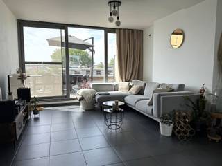 Zonnig dak-appartement op wandelafstand van het centrum van Mechelen met twee slaapkamers en een ruim zonneterras.Het gezellige appartement is toegankelijk via de inkomhal die uitgeeft op de woon- en eetkamer. De ruime ingebouwde kast in de inkomhal kan dienen als kleerkast of vestiaire-kast. Aanpalend aan de leefruimte is er de open ingerichte keuken voorzien van dubbele inox spoeltafel met verlek, vaatwasmachine, hete luchtoven, keramische kookplaat met dampkap, en koelkast met vriesvak. Aan de zijde van de achtergevel geeft de leefruimte via de grote raampartijen toegang tot het mooie ruime zonneterras.Vervolgens zijn de twee slaapkamers, één van 16 m², en een tweede van 13 m² voorzien van veluxramen met verduisterings- en horsysteem. De volledig betegelde badkamer omvat een ligbad voorzien van een douche-wand, toilet en enkele lavabo met meubel. Daarnaast is er ook een gastentoilet voorzien aan de woonst. Tot slot, heeft u voldoende opberg-mogelijkheden dankzij de ruime berging van circa 9 m² in het appartement (voorzien van aansluiting voor de wasmachine) en een gemeenschappelijke fietsenberging. Mogelijkheid tot aankoop ondergrondse parking (P45) met kelderberging mits 30.000euro