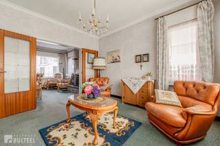 In een rustige straat doch op wandelafstand van het centrum bevindt zich deze ruime te renoveren woning. De woning biedt u op het gelijkvloers een inkomhal, een lichtrijke living, een spender, een keuken, een wasplaats/berging en een apart toilet. Op de eerste verdieping zijn er 3 slaapkamers waarvan 2 grote en 1 kleinere en een badkamer met lavabo en bad/douche. De ruime zolder is te bereiken via een schuiftrap maar kan in de toekomst perfect ingericht worden naar eigen smaak. Achter de woning bevinden zich nog twee ruime garages en een extra bergruimte, die eveneens dienst kunnen doen als opslagruimte.. Naast de woning is er plaats voor meerdere wagens. De ramen zijn voorzien van dubbele beglazing en rolluiken. Elektrische verwarming. Airco units aanwezig in de living en slaapkamer. In de directe omgeving van winkels, openbaar vervoer en school. Goede verbinding naar N16 en E17. Kortom, een ideale aankoop voor wie graag de handen uit de mouwen steekt.