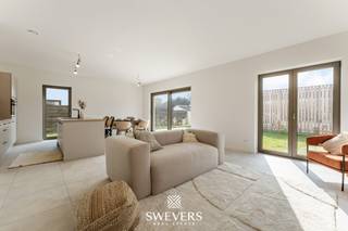 Voor meer info en foto’s, surf naar www.swevers.be – Dit recente gelijkvloerse appartement in residentie Oriole, gelegen in de Edward Stainstonstraat 4 A0.1 in Heusden-Zolder, combineert modern wooncomfort met een rustige ligging aan een natuurgebied. Het appartement werd gebouwd in 2024 en is volledig instapklaar afgewerkt met oog voor energiezuinigheid en praktisch wooncomfort.<br /><br />Met een bewoonbare oppervlakte van 129 m² beschikt het appartement over een ruime en doordachte indeling. De leefruimte van 23,85 m² sluit mooi aan op de open keuken van 18,75 m², waardoor een aangename en open woonomgeving ontstaat. Dankzij de grote raampartijen geniet u bovendien van veel natuurlijke lichtinval. Er zijn drie slaapkamers aanwezig van respectievelijk 13,07 m², 10,44 m² en 8,74 m². Deze ruimtes kunnen flexibel ingericht worden als slaapkamer, bureau of hobbyruimte. Verder zijn er twee badkamers voorzien, wat extra comfort biedt voor gezinnen of wie graag voldoende privacy heeft. Buiten geniet u van een terras van 16 m² met zuidoostelijke oriëntatie en een aansluitende tuin. Samen goed voor 44 m² buitenruimte waar u in alle rust kan ontspannen.<br /><br />Ook technisch scoort dit appartement uitstekend dankzij vloerverwarming, een eigen warmtepomp, zonnepanelen, ventilatiesysteem type D en superisolatie. Dit zorgt voor een aangenaam binnenklimaat en een lage energievraag. Verder is er een videofoon aanwezig. Het gebouw beschikt niet over een lift, kelderberging of staanplaats.<br /><br />De ligging combineert een groene en rustige omgeving met een vlotte bereikbaarheid. Winkels, horeca en ontspanning bevinden zich op wandelafstand. Scholen liggen op 800 meter, openbaar vervoer op 500 meter en de autosnelweg bereikt u op slechts 4,8 km.<br />Voor meer informatie, bel 011 255 155. Bron bewoonbare oppervlakte: EPC – verslag.