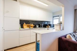 Op deze centrale ligging, gelegen nabij invalswegen, parken, scholen, winkels, ... vinden we dit netjes onderhouden appartementsgebouw. Het gerenoveerde appartement is gelegen op de 10e verdieping (lift aanwezig) en heeft volgende indeling: inkomhal met vestiaire, lichtrijke woonkamer met eetplaats, keuken met toestellen (koelkast, diepvries, oven, kookplaats, dampkap, vaatwasser), apart toilet, badkamer met douche, lavabo en aansluiting wasmachine, twee slaapkamers, waarvan één met balkon. Hier kan je genieten van een prachtig uitzicht over de skyline van Gent. Bij het appartement hoort ook nog een kelderberging en autostaanplaats. Het appartement is instapklaar! Huurprijs 1.200 euro/maand + 180 euro/maand (gemeenschappelijke kosten incl. verwarming en water). Vrij vanaf 01/07/2026.