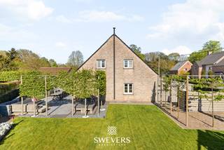 Voor meer info en foto’s, surf naar www.swevers.be – Deze open bebouwing in Helchteren (Ambachtstraat 33B) combineert ruimte, comfort en flexibiliteit. De woning uit 1996 werd goed onderhouden en deels geüpgraded met o.a. zonnepanelen en warmtepompboiler (2016), een nieuwe gasketel (2019) en een pelletkachel (2023). Met een bewoonbare oppervlakte van 225 m² biedt ze plaats voor het hele gezin.<br />Via de inkomhal met gastentoilet bereikt u de lichtrijke leefruimte van ca. 40 m² met zit- en eetgedeelte. Aansluitend ligt de praktische keuken (20 m²) met toegang tot tuin, wasplaats, garage en kelder. De inpandige garage (25 m²) biedt potentieel voor een studio, praktijk of kangoeroewonen gezien hier alle nutsvoorzieningen aanwezig zijn. Boven zijn er drie ruime slaapkamers (25 m² en 2 x 16 m² met inbouwkasten), een zeer ruime badkamer en een extra ruimte die kan dienen als dressing of bureau. Zelfs de overloop biedt ruimte voor een extra bureau of ontspanningsruimte. De kelder (31 m²) zorgt voor extra opslag.<br />Het perceel van 7a 59ca is zuidwest georiënteerd en beschikt over een recent aangelegde, verzorgde tuin met terras en veel privacy. Een bijgebouw van 40 m² biedt extra mogelijkheden als werkplaats of hobbyruimte. Rustig gelegen en toch nabij scholen, winkels (1 km) en vlotte verbinding via de autosnelweg (6 km). Voor meer informatie, bel 011 255 155. Bron bewoonbare oppervlakte: EPC – verslag.