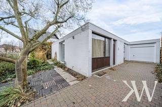 <em>Wie Katrien Wouters zegt, zegt vastgoed met een tikkeltje meer. En dat is niet zomaar.<br /><br />Deze brutalistisch-modernistische woning belichaamt het samenspel van architectonische finesse en eigentijdse leefkwaliteit. Het ontwerp is afkomstig van de hand van architect Adolf Nivelle, in co-creatie met de bouwheer, kunstenaar Toon Vanmechelen.</em><br /><br />Hier geen overdaad: zichtbaar beton, baksteen en hout tonen eerlijk hun structuur. Deze architectuur sluit aan bij een internationale beweging die eenvoud en functionaliteit benadrukt. Elk detail is doordacht, elke overgang zorgvuldig georkestreerd, met als resultaat een leefomgeving die niet alleen esthetisch intrigeert, maar ook functioneel tot in de puntjes klopt.<br /><br /><strong>Architecturaal geheel</strong><br />De woning presenteert zich als een monument van ingetogen kracht. Aan de straatzijde is het huis omhuld in privacy zonder het licht volledig buiten te sluiten. De witgeschilderde bakstenen gevel is strak, maar niet steriel. De geometrie is helder, de compositie evenwichtig, en het geheel wordt verankerd in een groene context die niet louter decoratief is, maar deel uitmaakt van de beleving.<br />Naar achteren toe opent de woning zich volledig. Grote raampartijen creëren een genereuze relatie met de tuin. De architectuur zoekt hier geen spektakel, maar rust en structuur – een helder kader voor het dagelijkse leven.<br /><br /><strong>Ruimtelijke helderheid en materiële rust</strong><br />De woning is opgebouwd volgens een doordachte structuur van beton, baksteen, glas en staal. Grote raampartijen verbinden binnen en buiten, terwijl horizontale lijnen ritme en stabiliteit brengen. Het resultaat is een leefomgeving die tegelijk open en geborgen aanvoelt. <br />Nivelle's architectuur staat in het teken van helderheid. Het gebruik van ruwe materialen, geometrische vormen en strakke lijnen zorgt voor een ingetogen maar krachtige uitstraling en geeft de woning een tijdloos karakter. <br /><br /><strong>Leefruimte in overvloed</strong><br />Binnenin ontvouwt de woning zich in een sequentie van ruimten die logisch op elkaar aansluiten, maar toch hun eigen sfeer behouden. De leefruimte is breed en licht, met warme houten vloeren, grote raampartijen en een ingebouwde kastenwand die zorgt voor rust en overzicht. Kunst krijgt een prominente plaats in het interieur en ook de koperen houthaard is een echte eyecatcher. De keuken is tegelijk functioneel en esthetisch: een strakke, heldere ruimte met een praktische opstelling. Op het gelijkvloers vind je daarnaast 4 slaapkamers, een badkamer, kunstatelier en een inpandige garage met geautomatiseerde sectionaalpoort. <br />                                                                                                                       <br /><strong>Integratie van kunstwerken</strong><br />De beeldhouwwerken in de voortuin en patio fungeren als symbool en verlengstuk van de architectuur. Kunst en gebouw zijn onlosmakelijk met elkaar verbonden. Meer dan een huis is dit een creatieve biotoop. Door zijn integrale ontwerpvisie creëerde de architect een omgeving die inspireert. <br /><br /><strong>Architectuur met toekomstpotentieel</strong><br />Deze woning is niet louter een object uit het verleden, maar biedt ook perspectief. Hoewel er energetisch werk aan de winkel is — het EPC-label F vraagt om renovatie — blijft de structuur bijzonder robuust. Dit is een pand dat vraagt om een eigentijdse interpretatie, zonder het originele karakter uit te wissen. Voor wie houdt van architectuur met ziel en geschiedenis, biedt deze woning een zeldzame kans.<br /><br /><strong>Meer ontdekken?</strong><br />Wil je graag thuiskomen in deze uitzonderlijke woning?<br />Contacteer mij dan snel voor meer info of een persoonlijk bezoek ter plaatse!<br /><br /><em>De vermelde oppervlaktes zijn slechts indicatief. Katrien Wouters - creating IMMOtions kan niet verantwoordelijk gesteld worden voor de juistheid van de aan haar verstrekte gegevens.  </em>