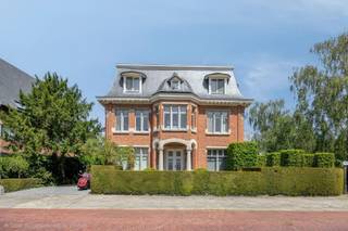Verkoop op aandelen.<br /><br />Een uitzonderlijke villa waar architectuur, elegantie en hedendaags comfort elkaar ontmoeten.<br /><br />Op een van de meest gegeerde locaties van Wilrijk, verscholen in de prestigieuze villawijk Den Brandt, bevindt zich deze karaktervolle residentie uit het interbellum. Een eigendom met een uitgesproken identiteit, waar historische architectuur en hedendaagse verfijning op een bijzonder natuurlijke manier samenkomen.<br /><br />De villa werd in 1924 ontworpen door de gerenommeerde architecten Gebroeders Wauters en getuigt vandaag nog steeds van de elegante beaux-artsarchitectuur uit die periode. De hoekligging aan de Sorbenlaan en Olmenlaan, de royale proporties en de aanwezigheid van authentieke elementen geven het pand een uitstraling die moeilijk te evenaren is.<br /><br />Achter de statige gevel ontvouwt zich een uitzonderlijk ruime woonbeleving van circa 600 m², met royale leefruimtes, originele parketvloeren, een stijlvolle leef- en eetkeuken en een sterke connectie met de aangelegde tuin.<br /><br />De woning beschikt over vijf slaapkamers, waaronder een bijzonder ruime master suite met dressing en een luxueuze badkamer.<br /><br />De leefkelder vormt een volwaardige ontspanningszone met onder meer een wellnessruimte met sauna en jacuzzi en een eigen home cinema.<br /><br />De tuin biedt, midden in de stad, een gevoel van rust en privacy dat vandaag bijzonder schaars is. De ligging nabij Park Den Brandt en de omliggende groene residentiële lanen combineert een discrete woonomgeving met een vlotte verbinding naar Antwerpen en de belangrijkste uitvalswegen.