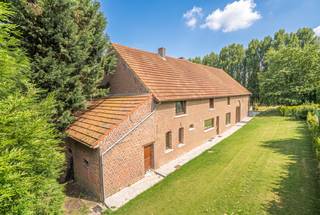 Vous êtes à la recherche d’un bien de caractère offrant de l’espace et de nombreuses possibilités ? Cette propriété unique mérite certainement une visite. Située sur un magnifique terrain de 1.228 m², elle combine une spacieuse maison familiale avec un espace polyvalent authentique.
Dès l’arrivée, le charme de la cour intérieure, les grandes terrasses et le jardin soigneusement entretenu attirent immédiatement l’attention. Grâce à son orientation nord-ouest, vous profitez à différents moments de la journée du soleil et de l’ombre, idéal pour apprécier pleinement les extérieurs tout au long de l’année.
Avec une superficie habitable de 281 m², la maison dispose d’un vaste espace de vie, d’une cuisine équipée, de trois chambres à coucher de belles dimensions, de deux salles de bains ainsi que de plusieurs espaces polyvalents pouvant être aménagés selon vos envies.
L’espace polyvalent constitue sans aucun doute l’atout majeur de cette propriété. Les poutres en bois apparentes, les murs en briques authentiques et les finitions chaleureuses créent une ambiance unique, devenue rare aujourd’hui. Cet espace plein de caractère offre de nombreuses possibilités : pièce de vie supplémentaire, atelier, espace de loisirs ou espace professionnel.
Les extérieurs représentent également un véritable atout. Le grand jardin, les différentes terrasses et l’environnement verdoyant en font un lieu idéal pour se détendre en toute tranquillité ou recevoir des invités. Malgré son cadre rural, la propriété se trouve à proximité des commerces, des écoles, des transports en commun et des principaux axes routiers vers Bruxelles.
La maison est équipée d’un chauffage central au mazout et bénéficie d’un label EPC E, offrant au futur propriétaire la possibilité d’améliorer davantage ses performances énergétiques.
Située en zone d’habitat à caractère rural, cette propriété offre une combinaison exceptionnelle de charme, d’espace et de potentiel dans un emplacement recherché à Sint-Pieters-Leeuw.
Un bien de cette qualité se présente rarement sur le marché. Contactez Claes &amp; Willems pour plus d’informations ou pour organiser une visite sur place.
