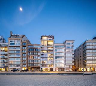 <p><strong>Luxe nieuwbouw duplex dakappartement met frontaal zeezicht – Zeedijk Het Zoute</strong></p>
<p>Uitzonderlijk ruim duplex dakappartement (gevelbreedte van 10,3 meter), ideaal gelegen op de Zeedijk tussen het Albertplein en de Wandeldijk in het Zoute. Een unieke combinatie van stijlvolle architectuur, overvloedige lichtinval en ongeëvenaard zeezicht.</p>
<p><strong>Indeling:</strong></p>
<ul>
<li>
<p>Inkomhal met gastentoilet en vestiaire</p>
</li>
<li>
<p>Royale leefruimte met een gevelbreedte van 10,3 meter, uitgevend op een ruim terras (2,5 m diep) met <strong>frontaal zeezicht</strong></p>
</li>
<li>
<p>Volledig uitgeruste luxe keuken (keukenbudget: €130.000) met zithoek en aparte bijkeuken, aansluitend aan een zonnig zuidgericht terras (2,25 m diep)</p>
</li>
<li>
<p>Technische berging</p>
</li>
<li>
<p>Slaapkamer 4 / bureau</p>
</li>
</ul>
<p><strong>Verdieping:</strong></p>
<ul>
<li>
<p>3 ruime slaapkamers met elk een eigen douchekamer (inloopdouche en toilet)</p>
</li>
<li>
<p>Master bedroom over de volledige gevelbreedte met dressing en luxe badkamer (ligbad, inloopdouche, toilet)</p>
</li>
<li>
<p>TV-hoek of bar met zicht op zee</p>
</li>
</ul>
<p><strong>Extra’s:</strong></p>
<ul>
<li>
<p>Vloerverwarming én -koeling via geothermie</p>
</li>
<li>
<p>Domoticasysteem</p>
</li>
<li>
<p>Grote fietsenberging op het gelijkvloers</p>
</li>
</ul>
<p>Een absolute topligging met hoogstaande afwerking en comfort, perfect voor wie op zoek is naar een exclusieve woonst aan zee.</p>
