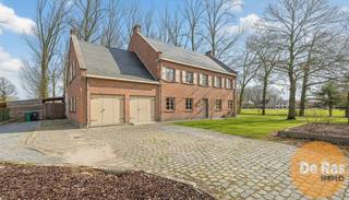 <strong>LEDE – Ruime villa met karakter op een ruim perceel</strong><br /><br />In het hart van Lede, op een rustige doch centraal gelegen ligging, treft u deze statige villa uit 1975, opgebouwd in traditioneel metselwerk en omgeven door een indrukwekkend perceel van 37a 84ca en palend aan agrarisch gebied. Bij binnenkomst wordt u verwelkomd in een centrale traphal die meteen toegang biedt tot de lichte en karaktervolle woonkamer. Grote raampartijen overspoelen de ruimte met natuurlijk licht en accentueren het tijdloze karakter van de woning, versterkt door massieve houten balken. De benedenverdieping biedt naast de woonkamer een aparte keuken, een bureau, een ruime berging en een zeer grote garage.<br /><br />Op de bovenverdieping bevinden zich zes ruime slaapkamers, waarvan drie zijn uitgerust met een eigen wasbak, aangevuld met een badkamer voorzien van ligbad, douche en dubbele wastafels. Extra comfort wordt geboden door een zeer ruime zolder die momenteel als stockage wordt gebruikt en een kruipkelder. In 2025 is een moderne aardgasverwarming geplaatst, waardoor comfort en energie-efficiëntie hand in hand gaan.<br /><br />De buitenruimte maakt deze villa uniek: een weelderig perceel met tal van volwassen bomen, een natuurlijke vijver en voorzieningen voor dieren, waaronder twee stallen en een aansluitende stockageruimte, naast een extra buitenberging. Deze woning combineert statige elegantie met praktische ruimte en een groene, rustgevende omgeving, terwijl scholen, winkels en verbindingswegen binnen handbereik liggen.<br /><br />Ontdek zelf deze prachtige villa en bel voor een afspraak op 053/60.65.60.<br />De prijs is een niet-bindende richtprijs. Na biedingen beslist de verkoper over verkoop aan het beste bod. Info via ons of reglement.