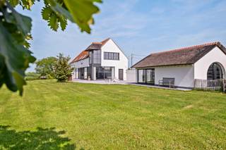 Op zoek naar een woning waar ruimte en natuur centraal staan, zonder in te boeten aan bereikbaarheid en comfort? Deze stijlvolle villa biedt een unieke woonervaring op een uitzonderlijk perceel van maar liefst 9.605 m², met een adembenemend uitzicht over de tuin, de achterliggende weilanden en de Blankenbergse Vaart die als het ware door uw achtertuin stroomt.<br /><br />De inkomhal met vestiaire en gastentoilet vormt de toegang tot de lichtrijke leefruimte, waar de grote raampartijen het prachtige verzicht maximaal tot hun recht laten komen. Het panoramische uitzicht over het omliggende groen zorgt elke dag opnieuw voor een instant vakantiegevoel.<br /><br />De ruime, uitgeruste keuken biedt voldoende plaats voor een grote eettafel. Aansluitend bevindt zich een praktische berging met aansluitingen voor wasmachine, droogkast en extra opslagruimte. Verder beschikt het gelijkvloers over een lichtrijke bureauruimte, ideaal voor thuiswerk of een vrij beroep, evenals is er de technische berging.<br /><br />Op de verdieping bevindt zich de master bedroom met dressing en een ensuite badkamer voorzien van een douche. Daarnaast zijn er nog twee volwaardige slaapkamers en een tweede badkamer met douche. Een extra troef is de grote open ruimte op de verdieping, die eenvoudig kan worden ingericht als vierde slaapkamer, hobbyruimte, speelkamer of bijkomende opslagruimte. De aanwezige zolder biedt bovendien nog extra bergruimte.<br /><br />Buiten bevindt zich een afzonderlijk bijgebouw dat momenteel gebruikt wordt als bureau, maar perfect kan worden ingericht als atelier, praktijkruimte, hobbyruimte,...<br /><br />De ligging combineert het beste van twee werelden: privacy in een groene omgeving, terwijl voorzieningen zich op minder dan vijf kilometer bevinden. Op een toplocatie tussen Brugge en de kust, een unieke kans voor wie droomt van wonen met een uitzicht dat nooit verveelt.<br /><br />Wenst u meer informatie of had u graag bezoek gepland? <br />Contacteer Fleur via 0477 82 85 42 of fleur.beernaert@acasa.immo