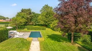 Deze luxueuze en zeer ruime stijlvolle villa van 380m² combineert een vakantiegevoel in eigen tuin met een zeer energiezuinig EPC A. <br />De prachtig aangelegde tuin van 18 are 30 ca met zonneterrassen biedt op elk moment van de dag een idyllische plek om in alle rust te genieten met familie en vrienden en het verwarmd openluchtzwembad van 10 x 3,6m maakt dit compleet.<br />Binnenin treft u een hoogwaardige afwerking en een zee van licht. <br />De doordachte indeling en de hoogwaardige materialen garanderen een maximaal leefcomfort.<br />Ontvangst: ruime inkomhal met vestiaire en gastentoilet.<br />Leefruimtes: lichtrijke ruime living 62m² met parket en inbouwhaard + aparte tv-kamer-bureel 18m².<br />Keuken: ruime volledig ingerichte leefkeuken met gezellige ontbijthoek-orangerie voor 8 personen – inrichting keuken is voorzien van recente toestellen en een praktische bijkeuken-berging.<br />Nachtgedeelte: 5 zeer ruime slaapkamers, 2 bad-of douchekamers, 2 dressings.<br />Praktisch: inpandige dubbele garage met automatische poorten en wasplaats, 3 toiletten en een zeer ruime bergzolder van 144m².<br />Bouwjaar: 2003 - zeer goede staat. Ki 3.580 euro.<br />Duurzaamheid: de woning beschikt over 20 zonnepanelen met een vermogen van 6.300 Wp (oost en west georiënteerd voor optimale verspreiding opbrengst) - een recente hoogrendement condenserend mazoutketel van 2020 met Tado systeem waarbij je per kamer apart kan verwarmen - zonneboiler - airco met warmtepomp op de 1ste verdieping - openluchtzwembad vernieuwd in 2026 en verwarmd met warmtepomp.<br />EPC 100 kwh/m² - energielabel A - UC2856004RERS1<br />Stedenbouwkundige info in aanvraag (woongebied met landelijk karakter en achterkant tuin agrarisch gebied - geen voorkooprecht ruimtelijke ordening).<br />Niet overstromingsgevoelig - gebouwscore A - perceelscore A.