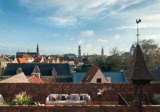 In het voormalige Karmelklooster, in het historische hart van Brugge, bevindt zich dit uitzonderlijke triplex appartement. Een unieke woonplek waar eeuwenoud erfgoed, hedendaags comfort en rust samenkomen.<br /><br />Het appartement bevindt zich in afwerkingsfase, waardoor u verschillende keuzes, waaronder de keuken, nog naar eigen smaak bepaalt.<br /><br />Via de inkomhal met vestiaire, gastentoilet en berging bereikt u de ruime eetkamer met authentieke houten balken en open keuken. Op dit niveau bevinden zich ook een bureau of extra slaapkamer met toegang tot de patio, en de master bedroom met ensuite badkamer met bad, douche, toilet en dubbele wastafel.<br /><br />Een verdieping lager vindt u de zithoek. De open verbinding met de eetruimte zorgt voor een bijzonder gevoel van hoogte en ruimte. Hier bevindt zich ook een extra slaapkamer met eigen badkamer. Via de patio van ca. 11 m² bereikt u het dakterras van ca. 30 m². U geniet er in alle privacy van een panoramisch uitzicht over de Brugse skyline.<br /><br />Als bewoner krijgt u bovendien toegang tot de prachtig aangelegde kloostertuin van ca. 5.000 m², met historische kloostergangen, fontein, grot en kapelletje.<br />Een zeldzame combinatie van erfgoed, ruimte, groen en privacy, op wandelafstand van alles wat Brugge te bieden heeft.<br /><br />Contacteer Nick Azou voor meer informatie of een bezoek via 0497/97.05.77 of nick.azou@istoir.be.<br /><br />