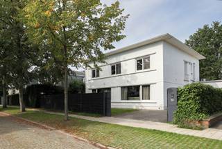 <p>Achter de witte gevel van deze vrijstaande villa wacht een ruime gezinswoning op een prachtig perceel van maar liefst 832 m².<br />We beginnen binnen.<br />De leefruimte is royaal en baadt dankzij de vele ramen in het daglicht. Een grote zithoek om languit te verdwijnen in de zetel, een eetplaats waar zonder moeite familie en vrienden aanschuiven. Aansluitend ligt de keuken, praktisch ingericht en met zicht op het groen. Daarnaast bevindt zich nog een handige berging.</p>
<p>En wie denkt dat we daarmee alles op het gelijkvloers gezien hebben, heeft het mis...<br />Vanuit de berging wandel je namelijk verder naar de <strong>poolhouse</strong>. Al doet die naam de ruimte eigenlijk wat tekort.<br />Hier werd een studio ingericht, compleet met eigen slaapkamer en een badkamer. Bovendien heeft ze ook een aparte toegang van buitenaf.<br />Een tiener die stilaan droomt van wat meer zelfstandigheid? Logés die graag blijven slapen, maar ook hun eigen plek appreciëren? Een au pair?</p>
<p>Achter de woning ligt een heerlijk diep perceel, omringd door volwassen groen. Een groot terras loopt over in de tuin en helemaal achteraan zorgen de hoge bomen voor privacy.<br />En dan hebben we het zwembad nog niet gehad.<br />Want ja… <strong>hier zwem je gewoon thuis.<br /></strong>Het ruime zwembad werd gerenoveerd en kreeg een volledige overkapping. Op frissere dagen zwem je beschut, zodra de zon zich laat zien kan de constructie worden geopend en verandert het geheel in een heerlijk buitenbad.<br />Baantjes trekken voor het ontbijt? Een frisse duik na het werk?<br />Of kinderen die op een zomerdag alleen nog uit het water komen omdat er eten op tafel staat?<br />Wij zien het alvast gebeuren!<br />En het fijne is: ondanks het zwembad blijft er nog méér dan voldoende tuin over. Om te voetballen, te spelen, languit in het gras te liggen of gewoon te genieten onder de bomen.<br />Op de 1<sup>ste</sup> verdieping bevinden zich <strong>vier slaapkamers en twee badkamers</strong>.</p>
<p>De woning dateert oorspronkelijk uit 1970 en werd in 2016 gerenoveerd.<br />Verwarming gebeurt via een condensatieketel op gas en ook een alarmsysteem is aanwezig.<br />En dat allemaal op een bijzonder gegeerde locatie in de <strong>Elsdonkwijk</strong>.</p>
<p>Het enige gevaar?<br />Dat vrienden plots opvallend vaak voorstellen om bij jullie af te spreken.</p>
<p>Troeven:<br />- Vrijstaande villa in de Elsonkwijk<br />- Prachtig diep en groen perceel<br />- Overdekt zwembad, volledig te openen<br />- Ruim terras en veel tuinruimte<br />- Royale en lichtrijke leefruimte<br />- 5 volwaardige slaapkamers<br />- 3 badkamers<br />- Berging<br />- Garage / studio / hobbyruimte / poolhouse<br />- Renovatie in 2016<br />- Condensatieketel op gas<br />- Alarmsysteem<br />- Goede en praktische indeling</p>
