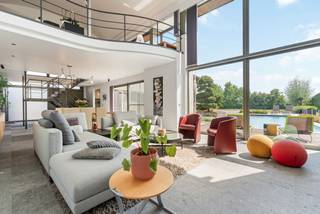 Deze uitzonderlijke luxevilla, gebouwd in 2007, bevindt zich op een prachtig zuidgeoriënteerd perceel van 27are 24ca in de idyllische Velpvallei. De woning van 391m² (vlgs opgave EPC) geniet van een rustige ligging aan de rand van de dorpskern en biedt een schitterend uitzicht over uitgestrekte akkers en boomgaarden.<br /><br />Bij het ontwerp werd gekozen voor hoogwaardige en duurzame materialen die doorheen de volledige woning werden doorgetrokken. De gevel werd afgewerkt met Belgische arduin Roestenburg, terwijl op het gelijkvloers dezelfde Belgische arduin in een gebouchardeerde uitvoering werd toegepast als vloerbekleding. Dit zorgt voor een tijdloze en luxueuze uitstraling.<br /><br />Via de imposante inkomdeur betreedt u de ruime inkomhal met stijlvolle industriële trap. Dankzij de plafondhoge raampartijen staat de leefruimte volledig in verbinding met de tuin, het terras en het zwembad, waardoor binnen- en buitenleven naadloos in elkaar overvloeien. Bovendien werd reeds een liftschacht voorzien, wat de woning toekomstbestendig maakt.<br /><br />Gelijkvloers<br /><br />Het gelijkvloers wordt gekenmerkt door een uitzonderlijk gevoel van ruimte en licht. U vindt er een vestiaire en afzonderlijk gastentoilet, een royale leefruimte met grote schuiframen naar het terras en het zwembad, en een kwalitatief afgewerkte leefkeuken met maatwerk, een Atag-kookplaat, Miele-toestellen en een tijdloos inox werkblad. Verder beschikt deze verdieping over een praktische voorraadruimte, een inpandige garage, technische ruimte en aansluitend een poolhouse uitgerust met wastafel, toilet en inloopdouche.<br /><br />Verdieping<br /><br />De nachthal geeft toegang tot een ruime slaapkamer met ensuite badkamer voorzien van douche, wastafel en toilet. In de vide boven de leefruimte werd een zwevende bureauruimte geïntegreerd, die zorgt voor een unieke architecturale toets. Daarnaast beschikt de woning over een stijlvolle dressing op maat, verbonden met een luxueuze badkamer afgewerkt met Italiaans Carraramarmer en uitgerust met dubbele wastafel, inloopdouche, ligbad en toilet. Aansluitend bevinden zich de master bedroom en een fitnessruimte met infraroodsauna en overdekt terras, die desgewenst kan worden ingericht als extra slaapkamer.<br /><br />Technieken en comfort<br /><br />Ook technisch voldoet deze villa aan de hoogste normen. De woning wordt verwarmd via een geavanceerde gas-elektrische warmtepomp met vloer- en luchtroosters. Airconditioning zorgt voor aangename verkoeling tijdens warme dagen. Het zwembad wordt afzonderlijk verwarmd via een warmtepomp, terwijl 36 zonnepanelen op een esthetische manier werden geïntegreerd in de tuin.<br /><br />Tuin en buitenruimtes<br /><br />De volledig omheinde tuin werd met veel zorg aangelegd en biedt een uitzonderlijk gevoel van rust en privacy. Het ruime zonneterras en het verwarmde zwembad vormen een heerlijke plek om te ontspannen en te genieten van de zuidgerichte oriëntatie. Via de automatische toegangspoort betreedt u het domein in alle comfort en discretie.<br /><br />Bijzonderheden<br /><br />EPC-label B<br />Exclusieve en luxueuze afwerking<br />36 zonnepanelen<br />Centraal stofzuigsysteem<br />Voorzien van liftschacht<br />Verwarmd zwembad met poolhouse<br />Volledig omheind perceel van 27a 24ca<br />Unieke ligging in de Velpvallei met prachtig verzicht over akkers en boomgaarden<br />Zuidoriëntatie met maximale privacy
